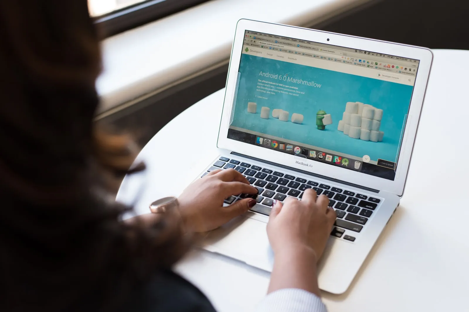 A person typing on a laptop in a bright office