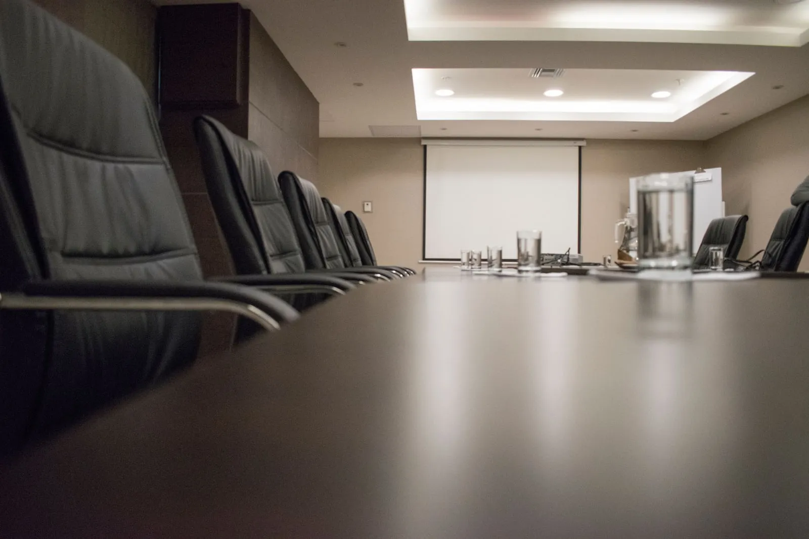 An empty boardroom with a long table and glass walls
