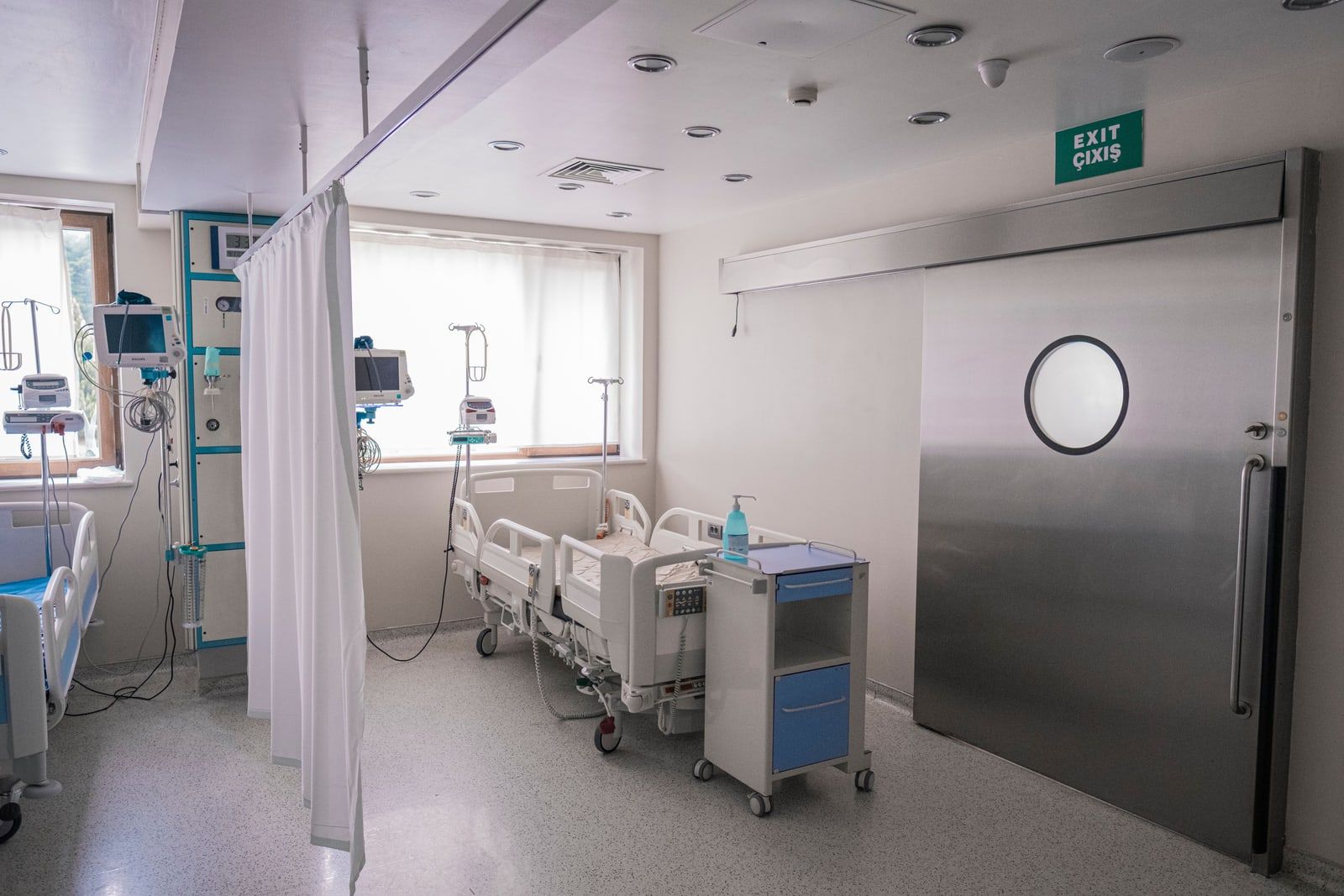 A hospital room with a bed, monitors and a curtain rail