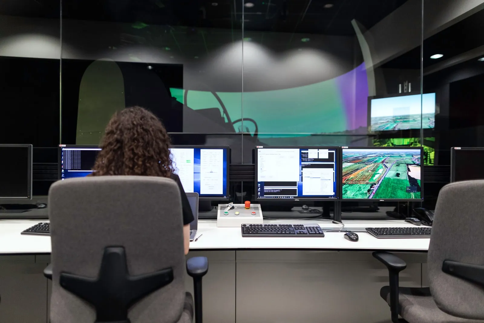 A person at a desk of monitors in a control room