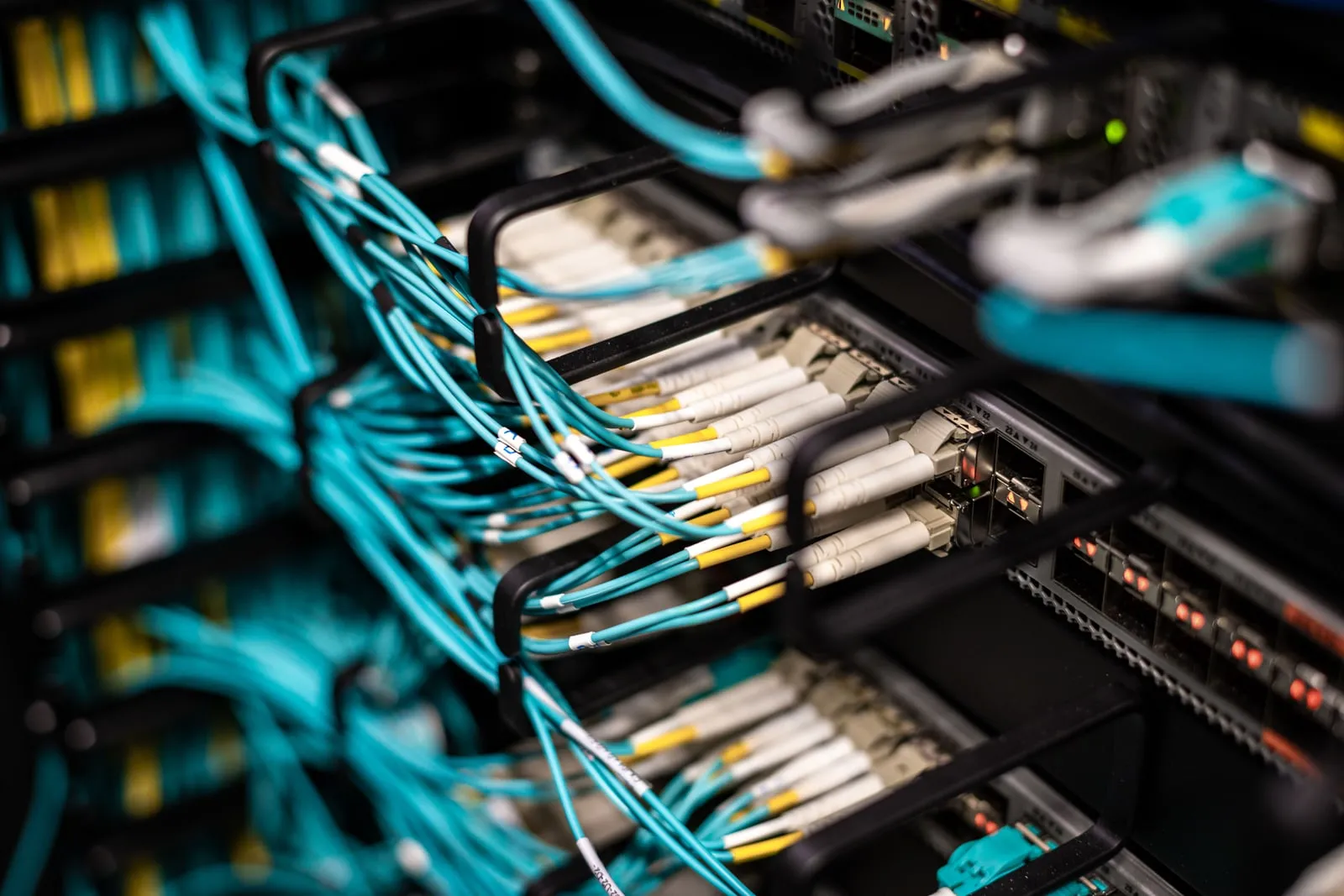 Fibre optic cables plugged into equipment in a data centre rack