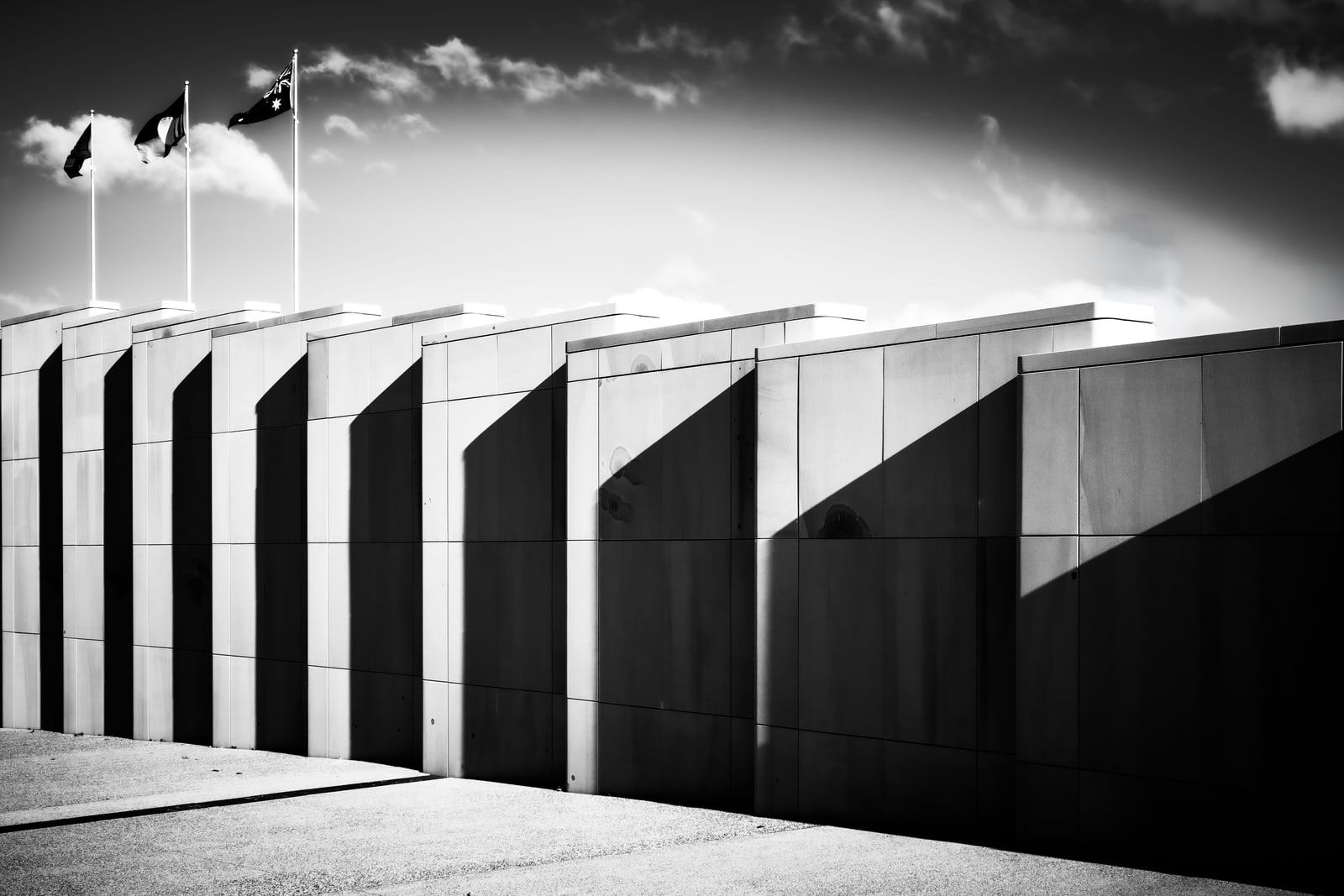 Australian flags flying above the stone facade of a government building in Canberra