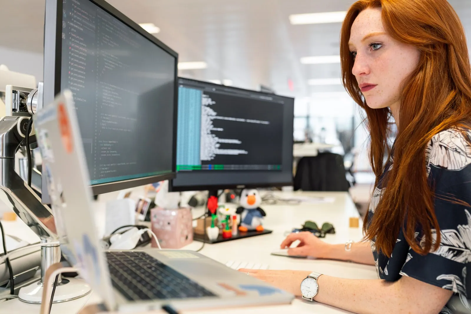 En programmør der arbejder ved et skrivebord med to skærme