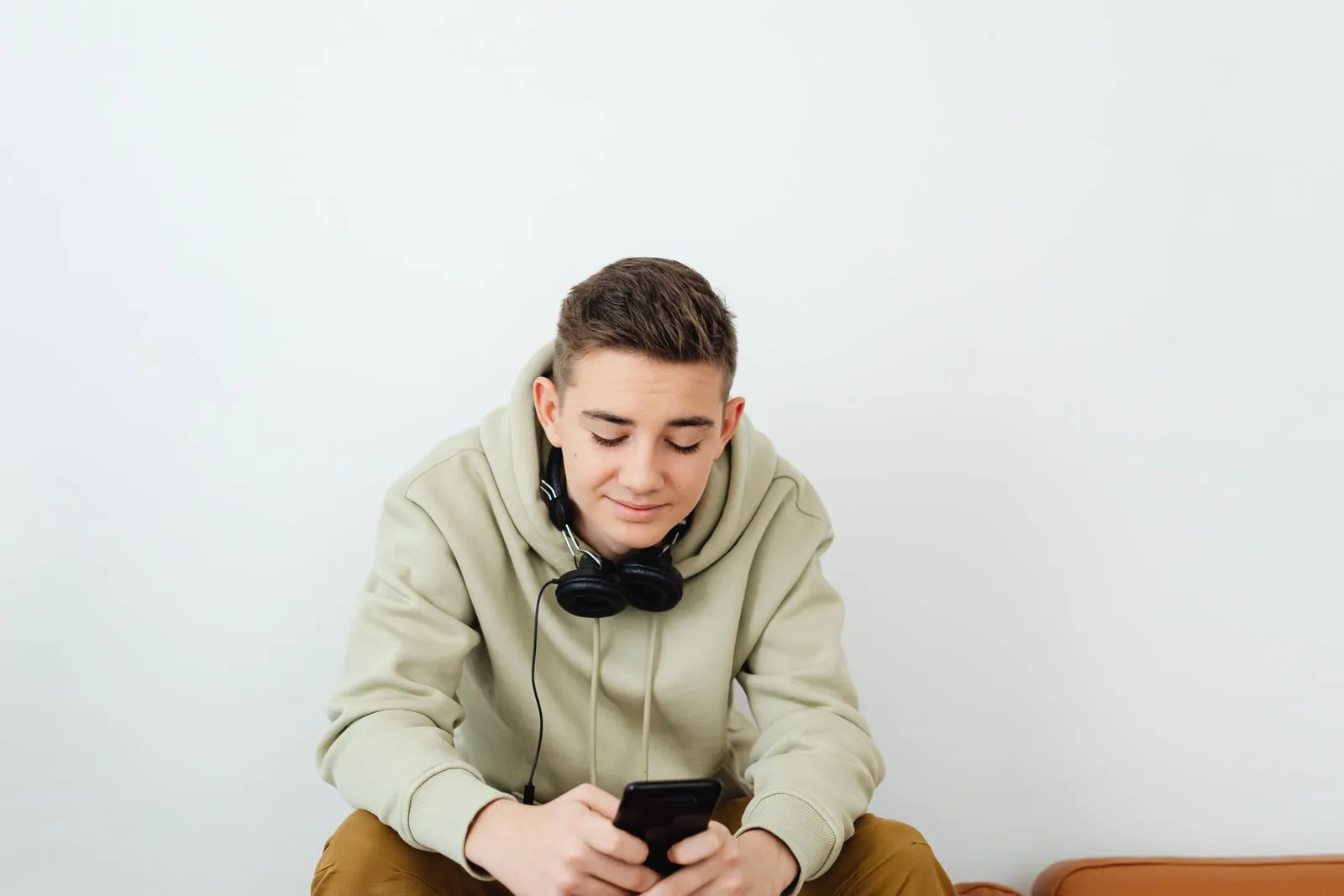 A young person with headphones around their neck looking at a phone