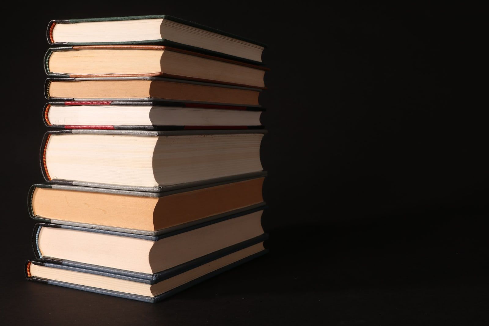 A stack of hardback books against a dark background
