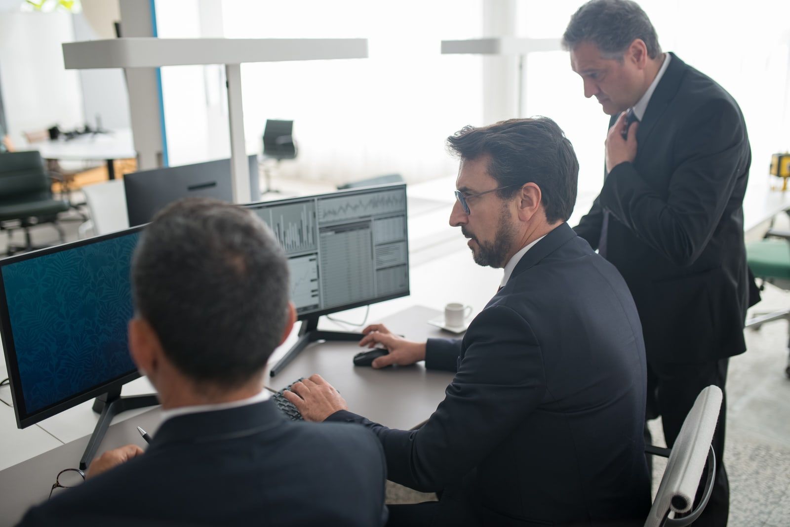 Office workers at desks with computer monitors in an open-plan office