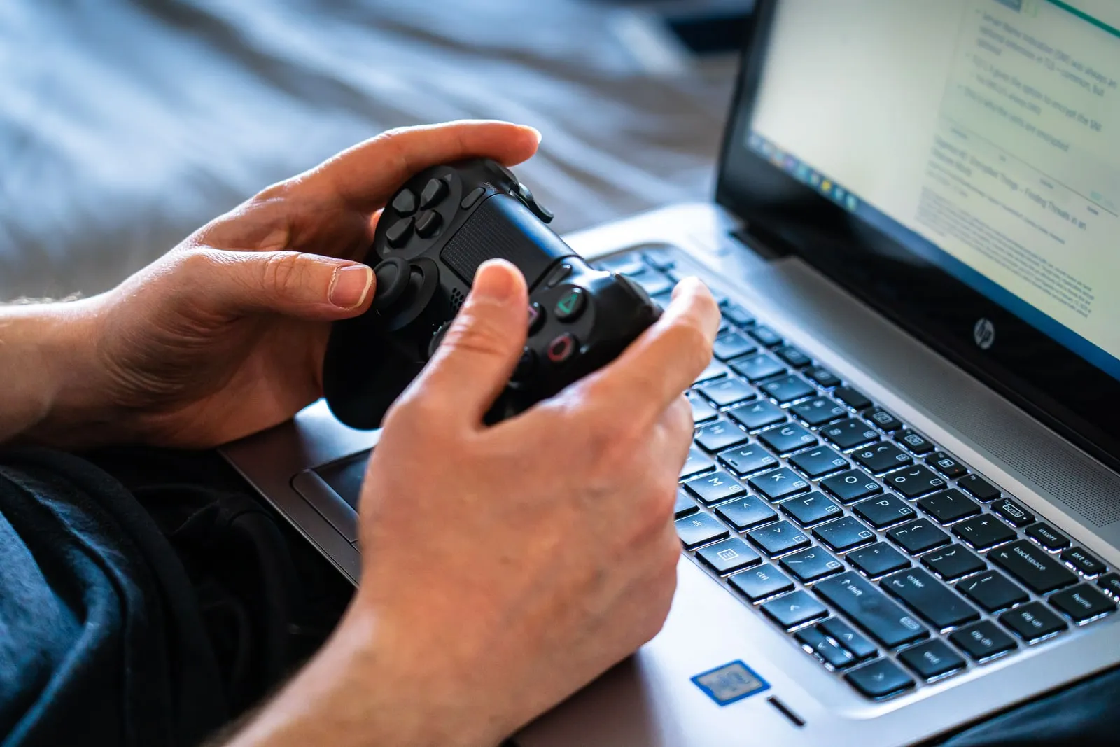 Hands holding a game controller over a laptop keyboard