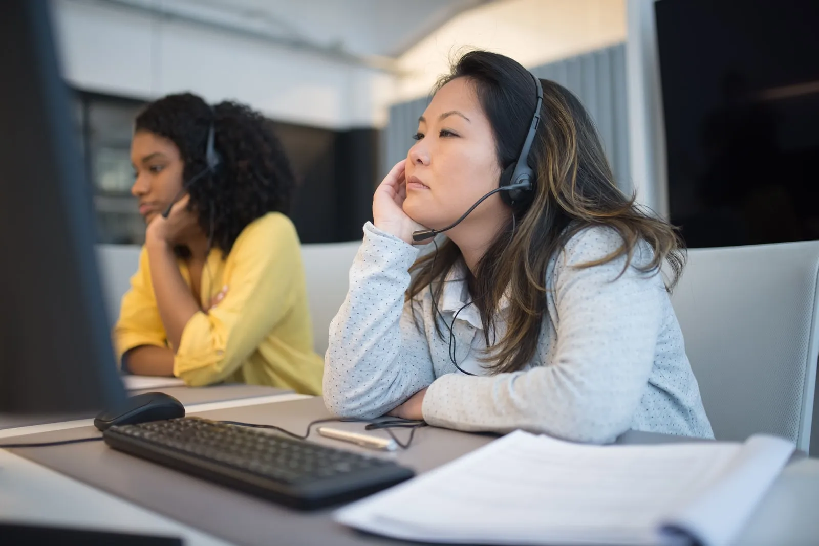 Two people wearing headsets at a call centre desk