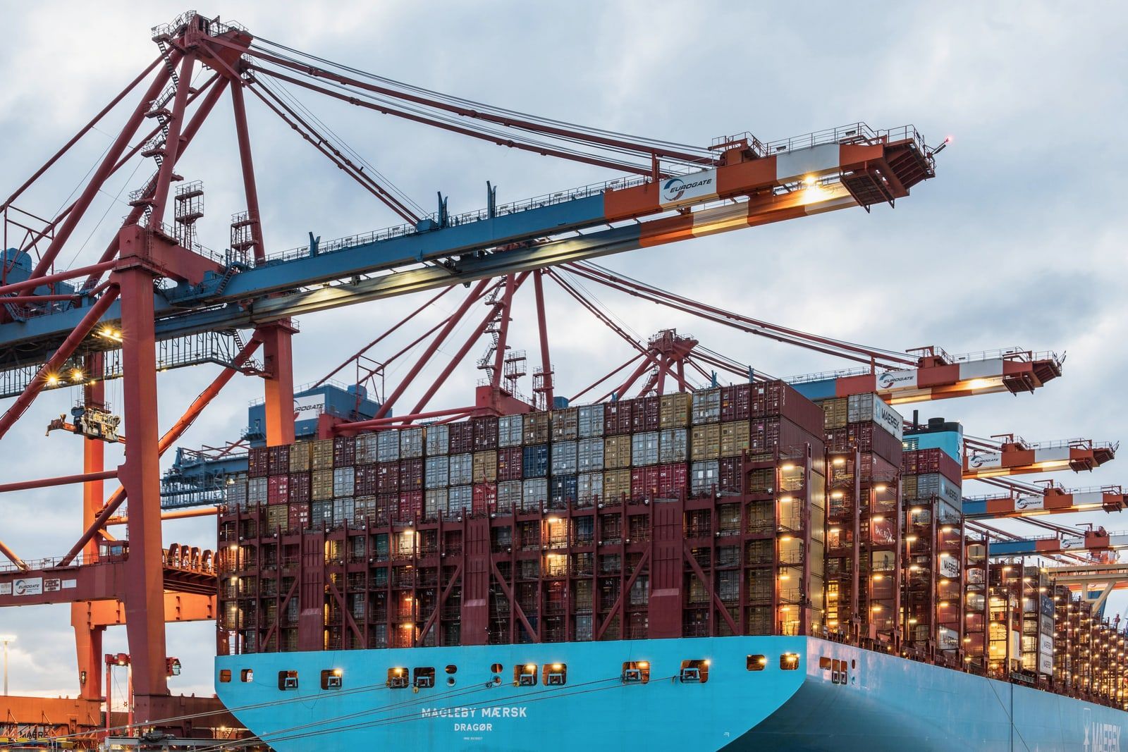 A container ship being loaded by gantry cranes at a port terminal