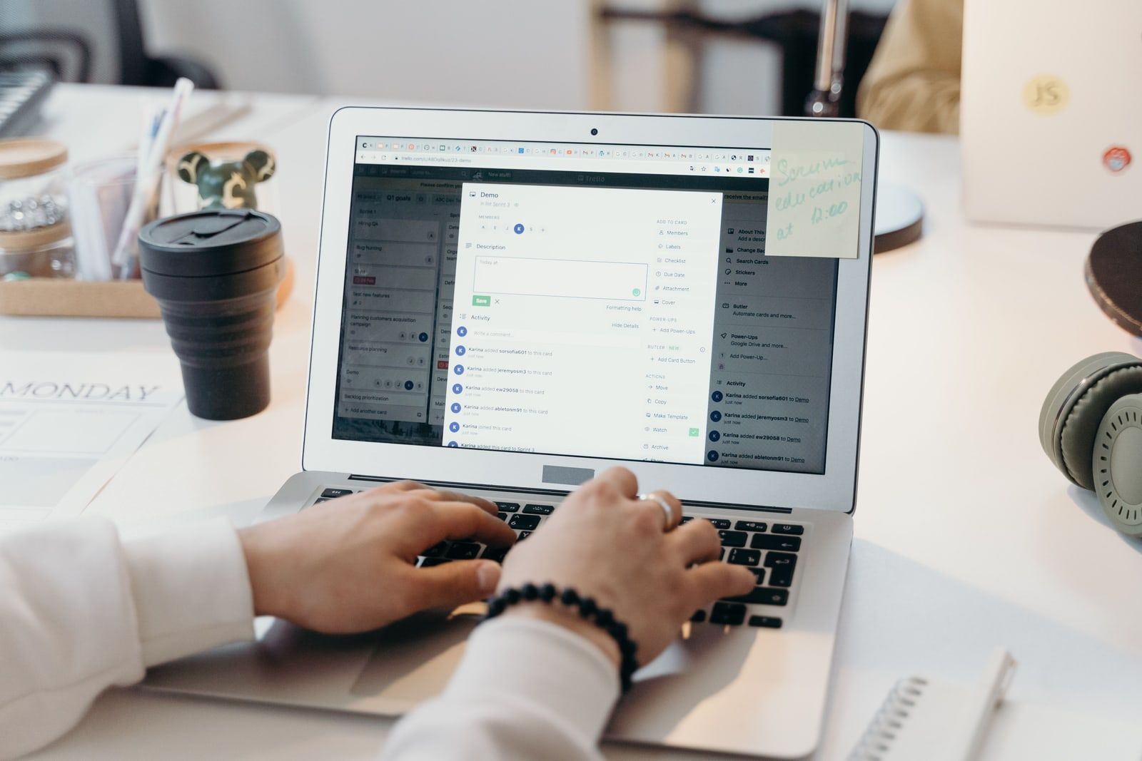 Hands typing on a laptop showing a task board on screen
