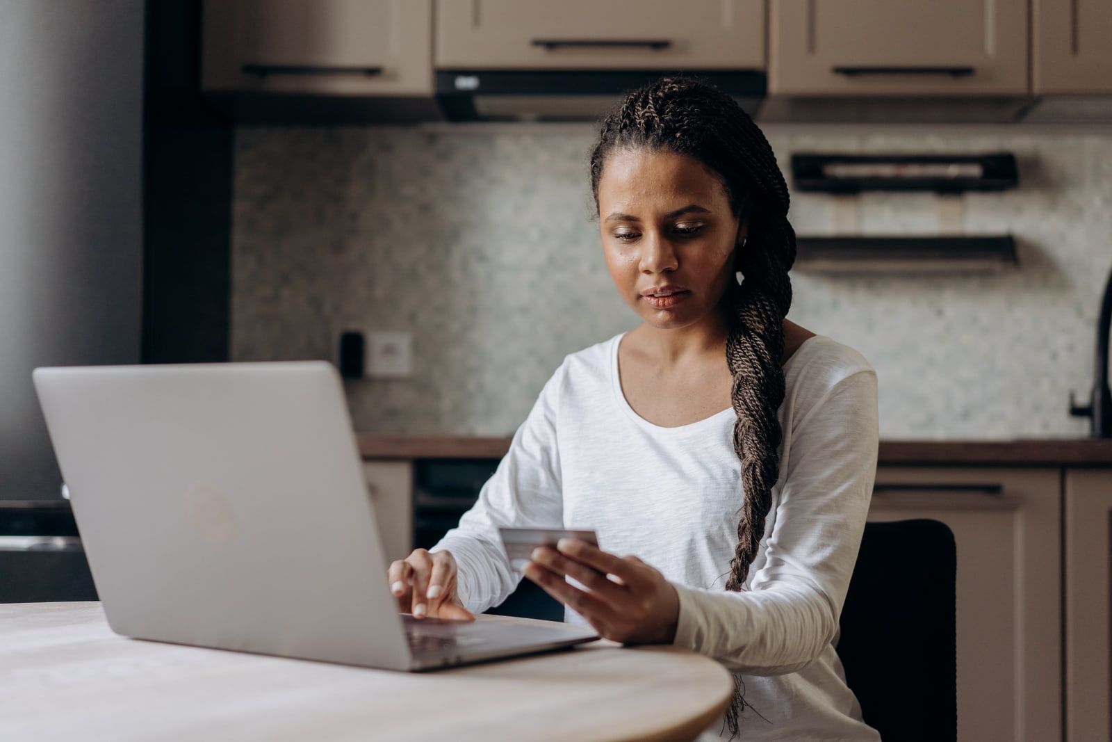 A person shopping online on a laptop at a kitchen table