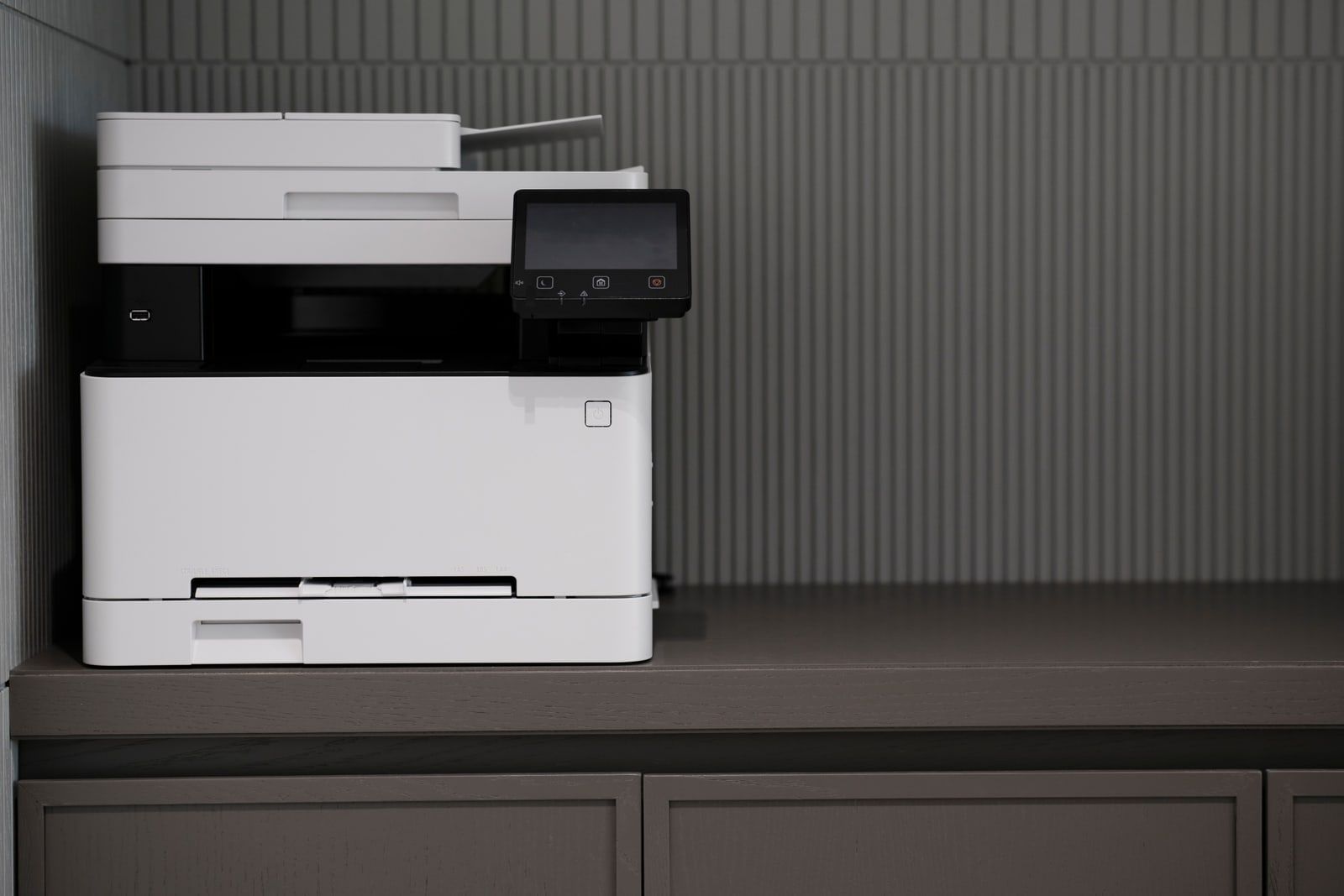 An office photocopier standing against a wall