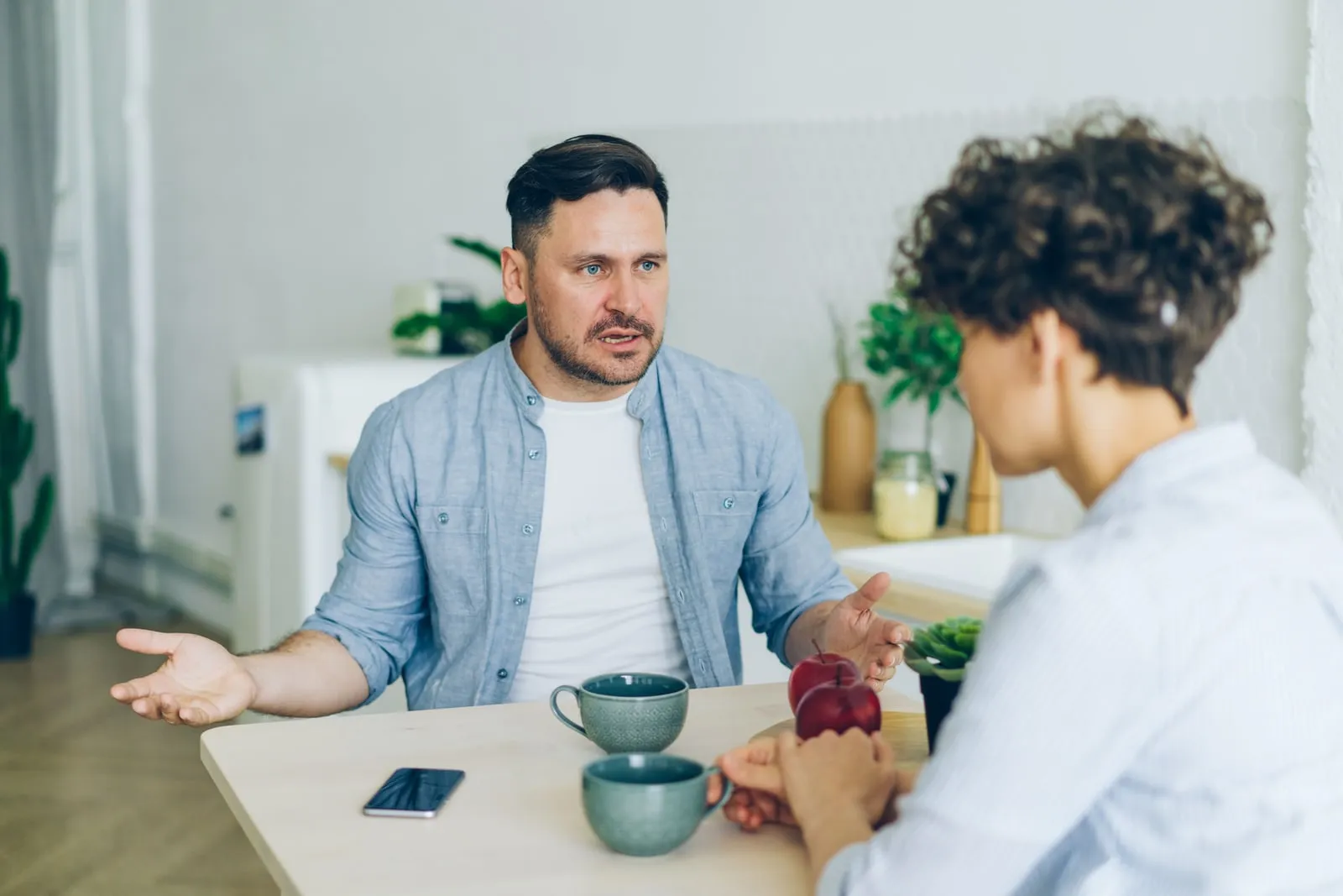 Two people talking across a table in a bright room