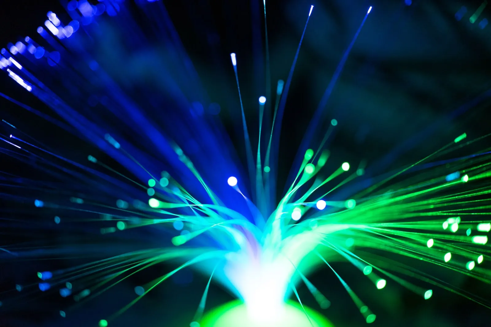 Illuminated optical fibres fanning out in blue and green
