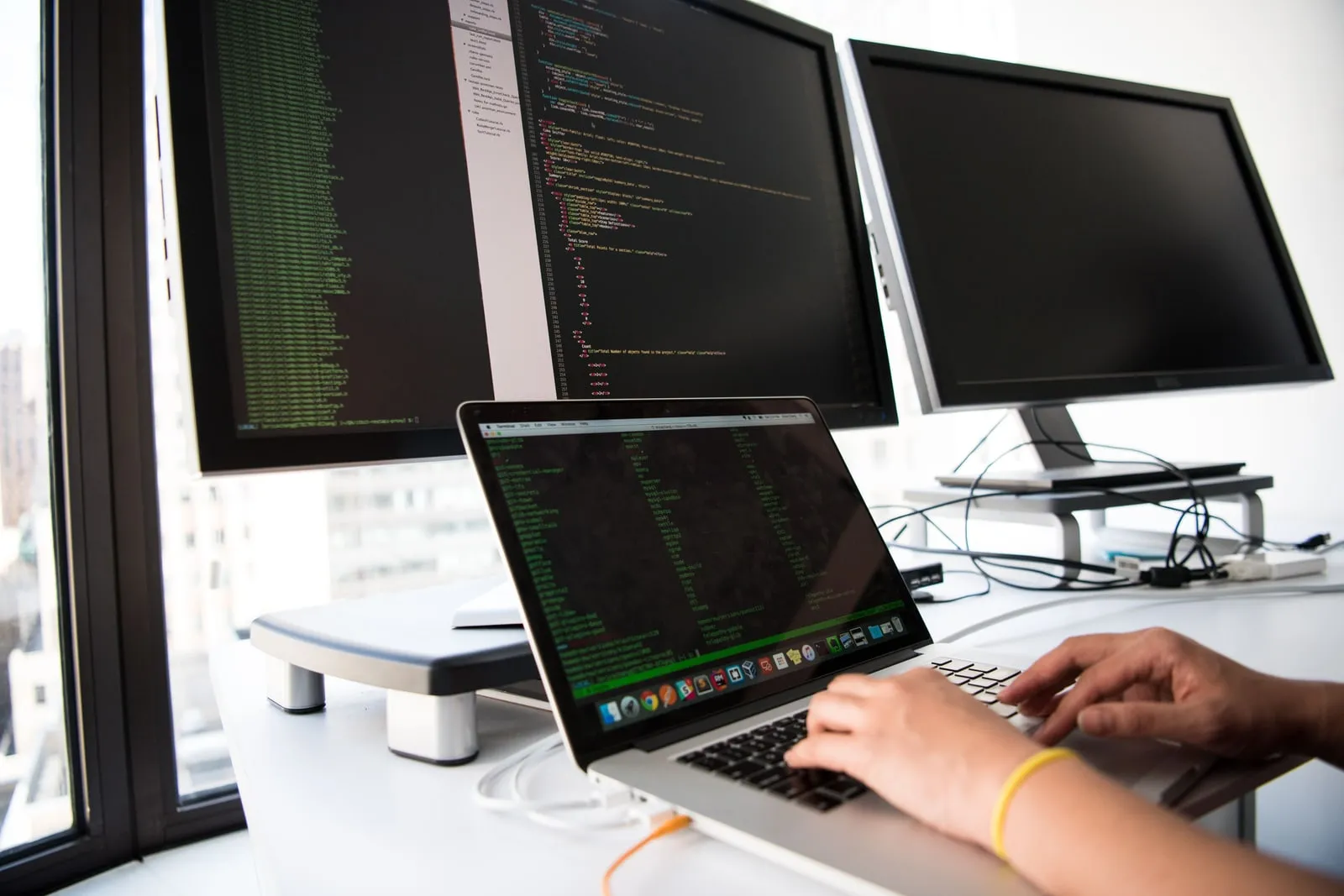 A developer reviewing code on two monitors