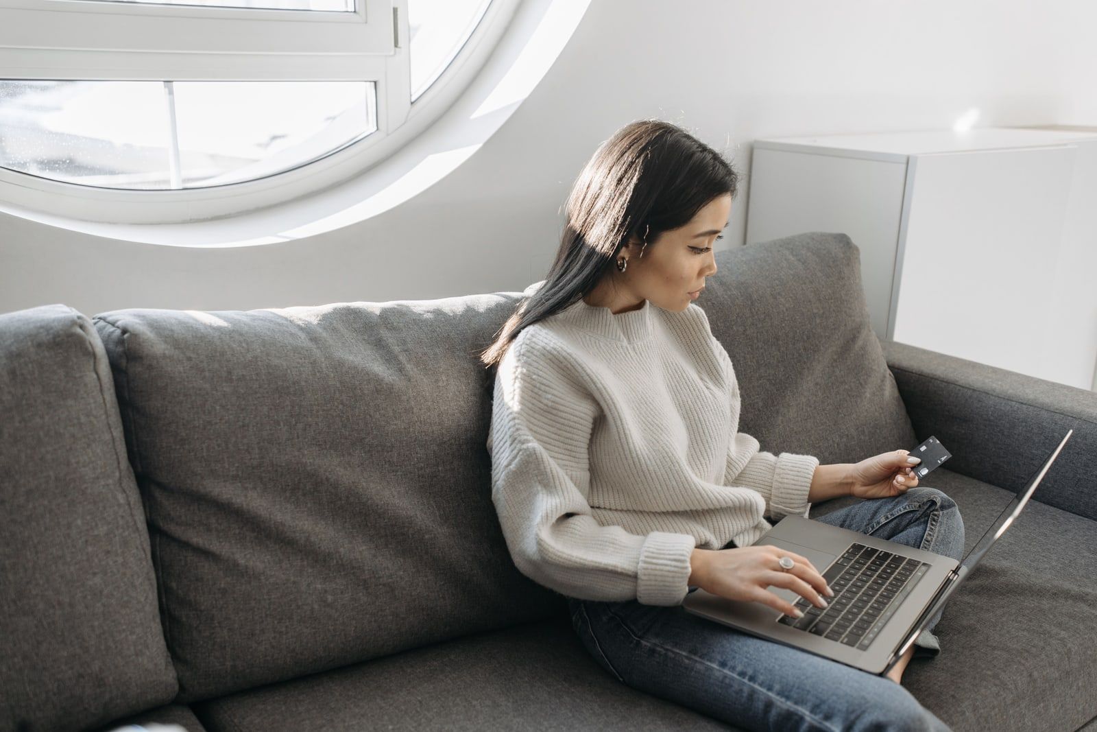 Woman shopping online on a laptop while sitting on a sofa