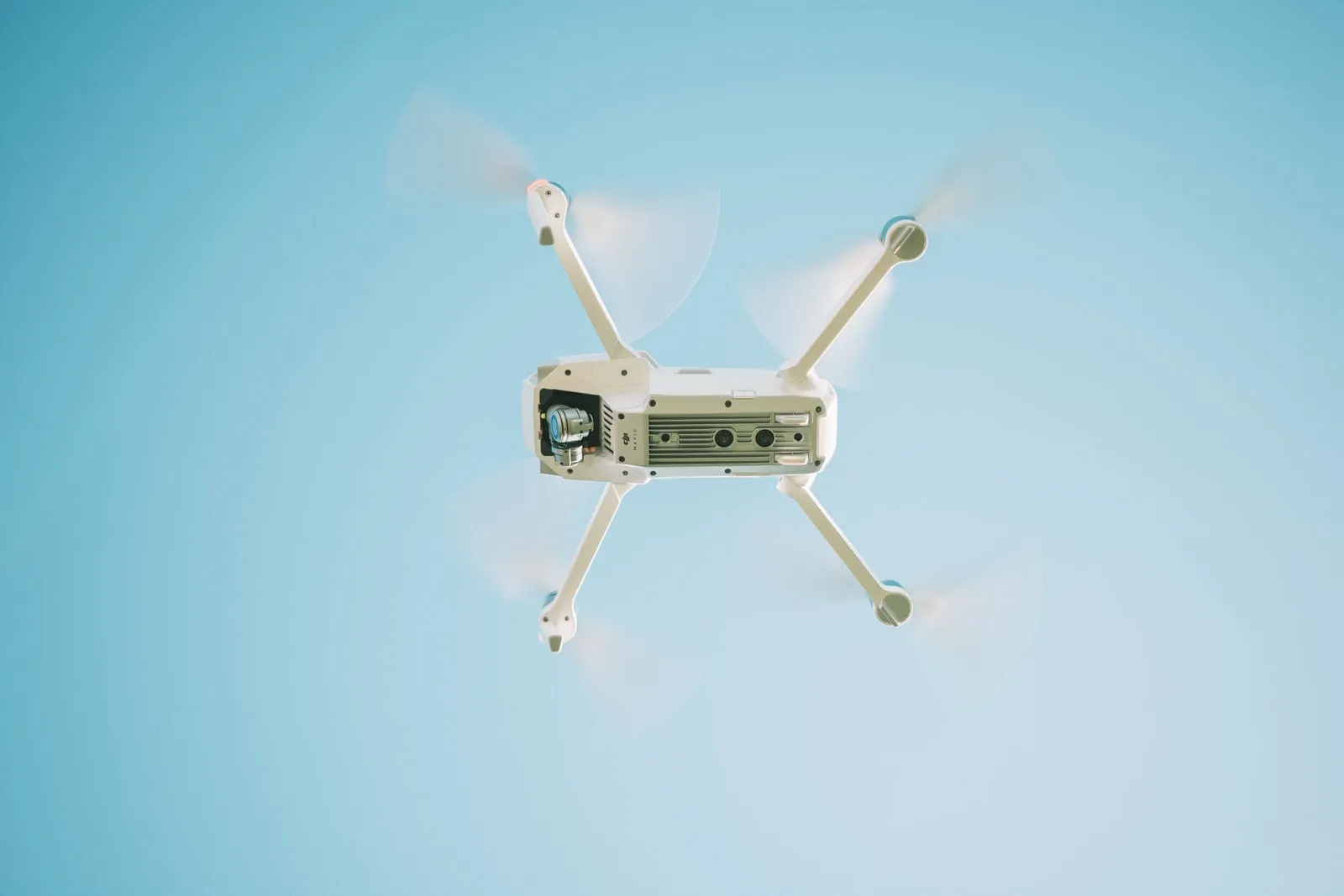 A small quadcopter drone flying against a clear sky