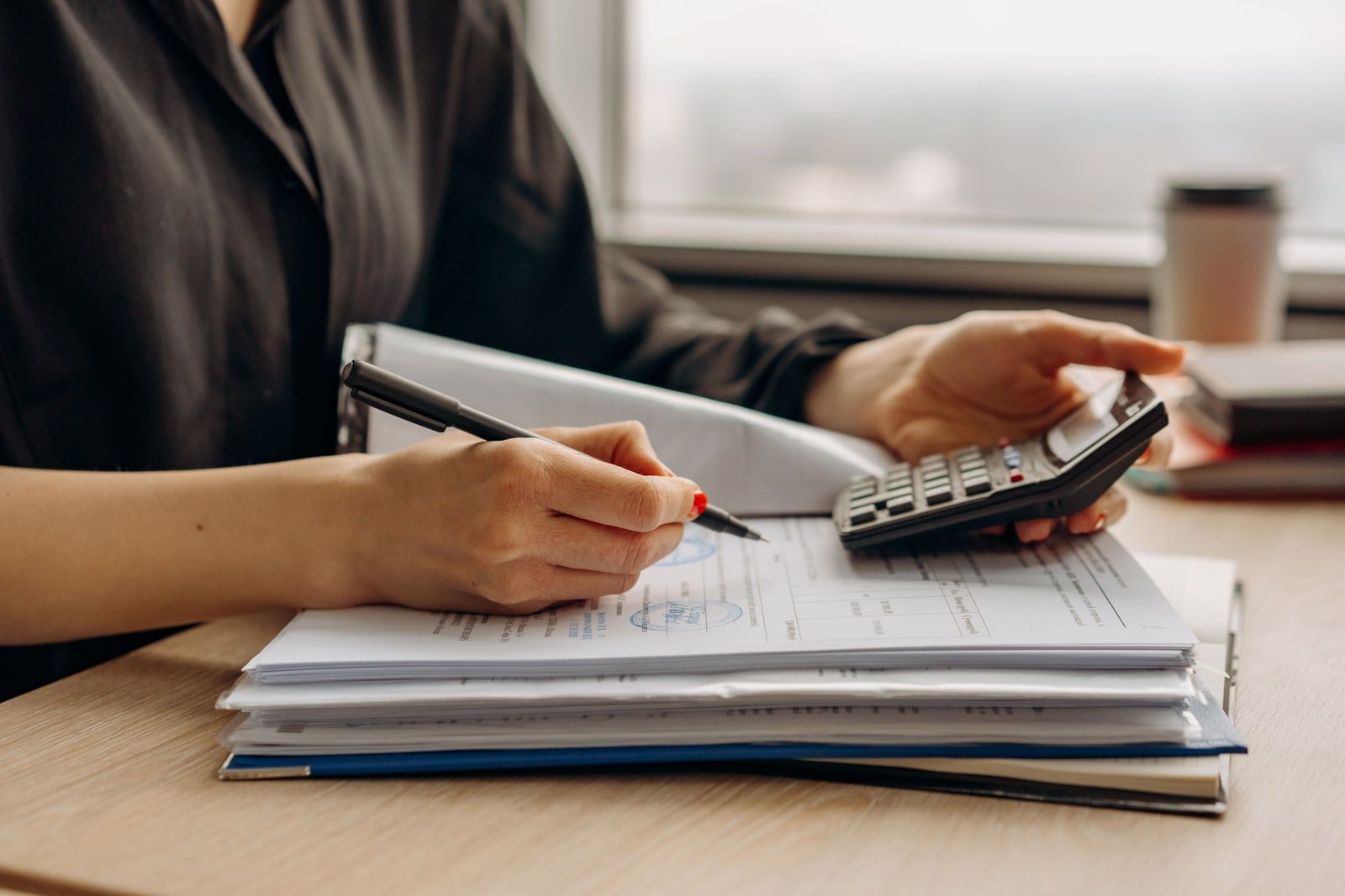 A person reviewing paperwork with a calculator at a desk