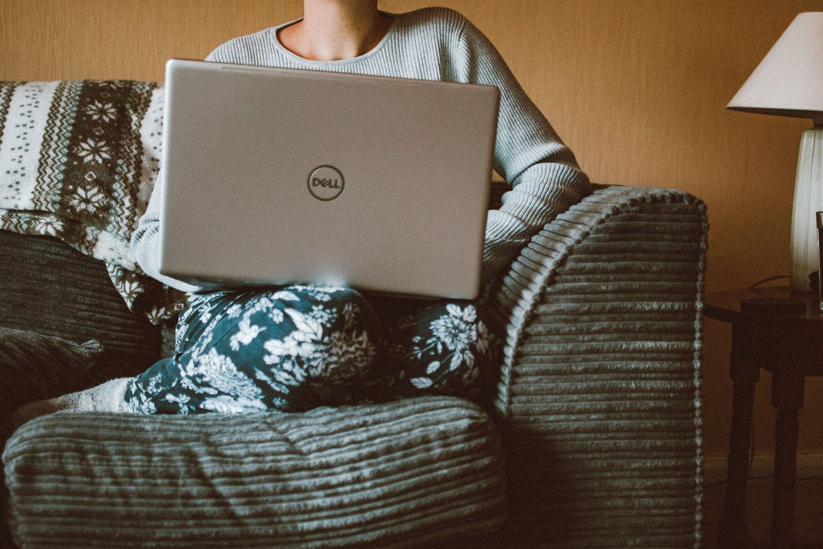 A person sitting on a sofa at home working on a laptop
