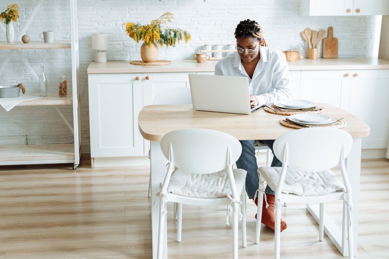 Person typing on a laptop at a kitchen table