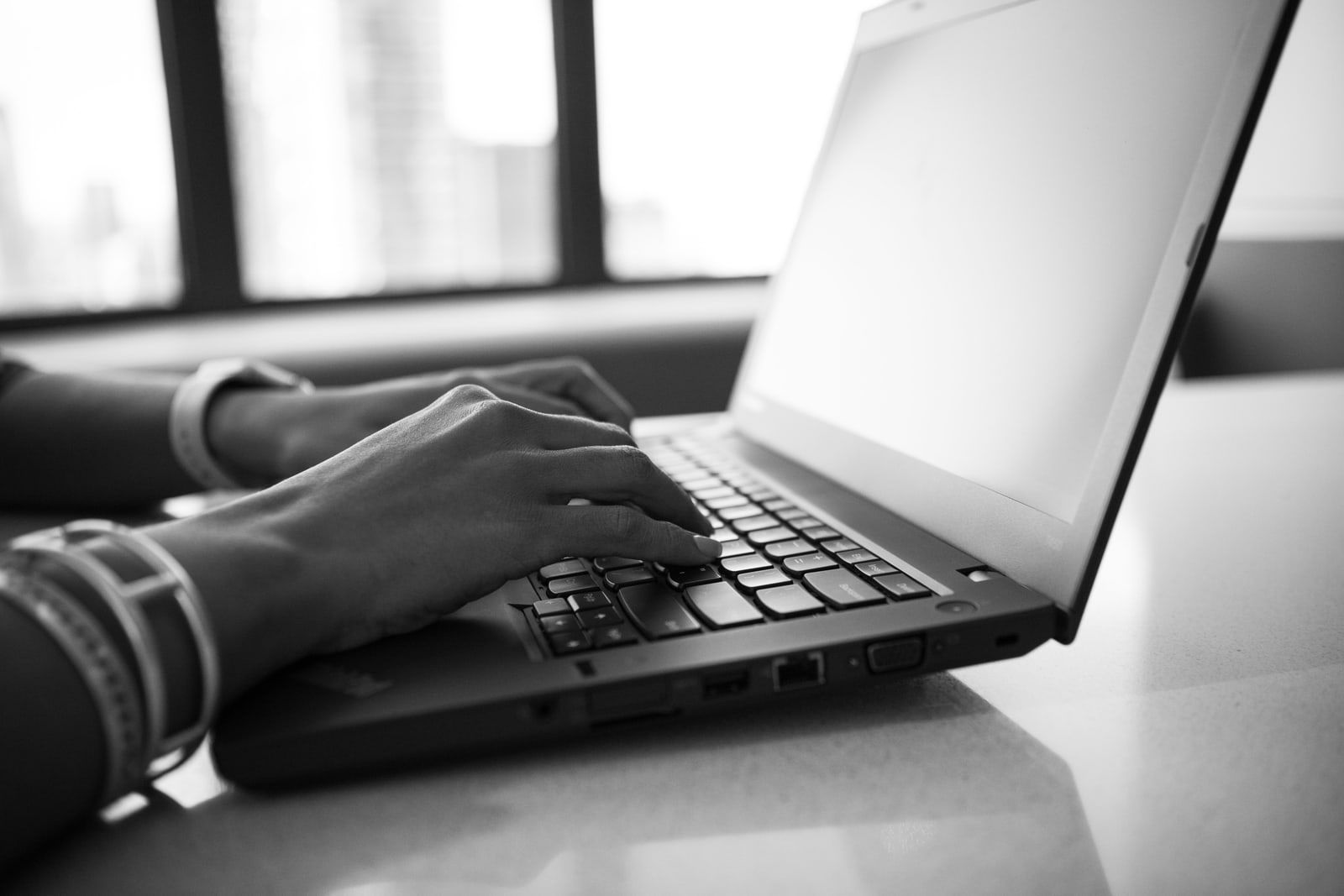 Hands typing on a laptop keyboard at a desk
