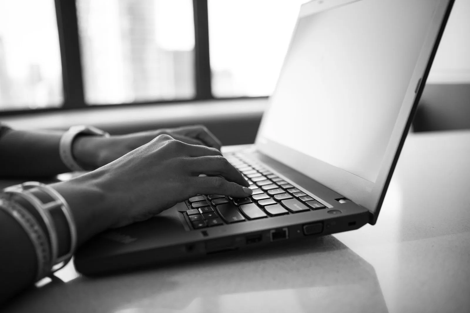 Hands resting on a laptop keyboard at a desk