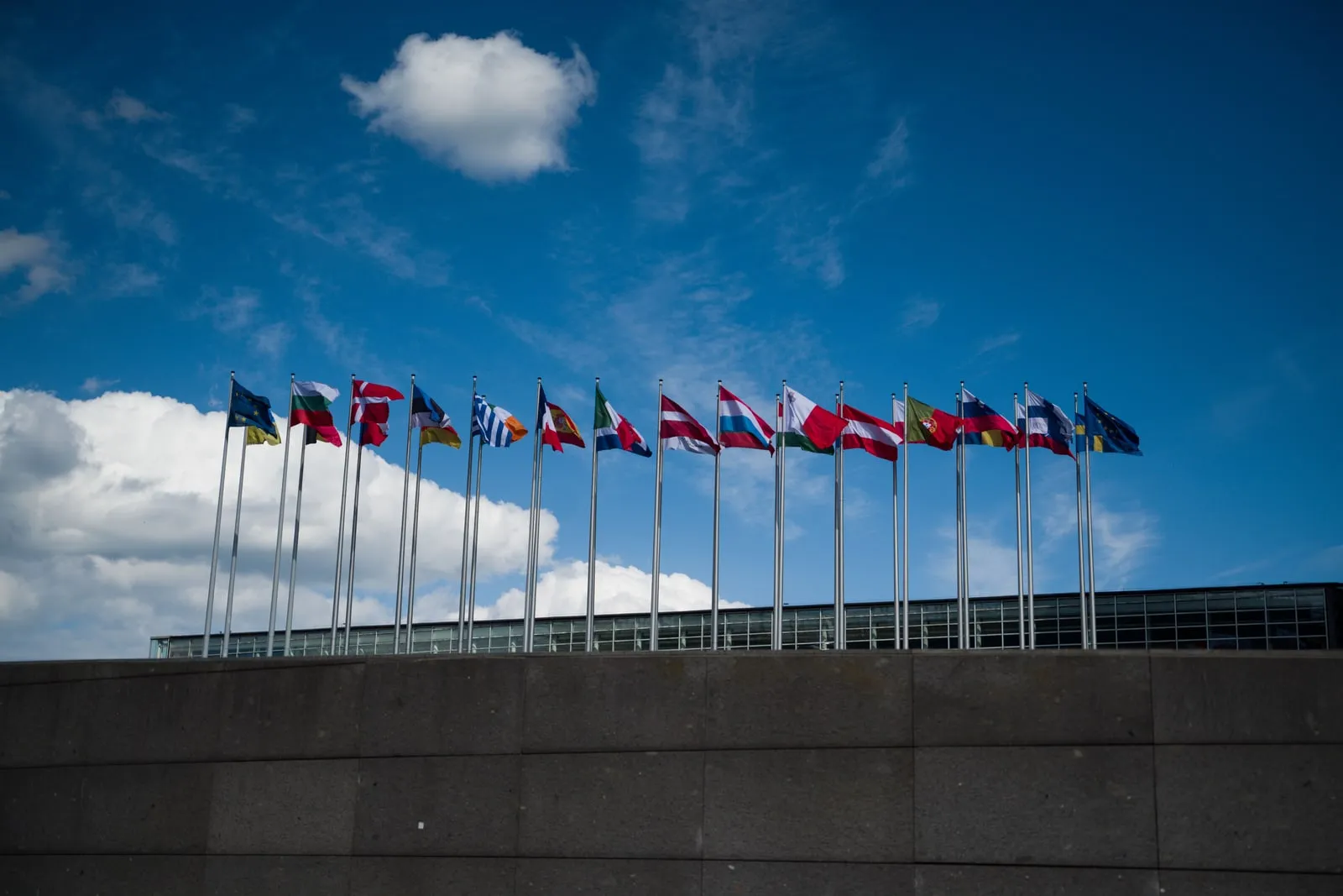 A row of national flags flying on flagpoles outside a building