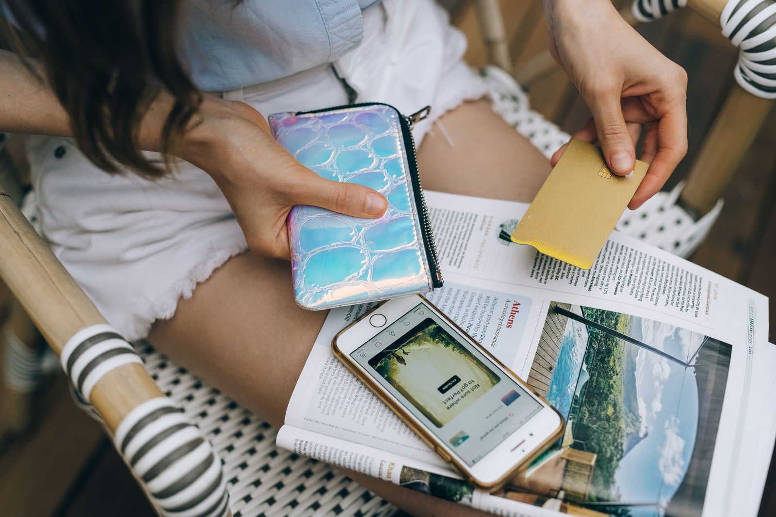 A person holding a wallet and a payment card beside a phone