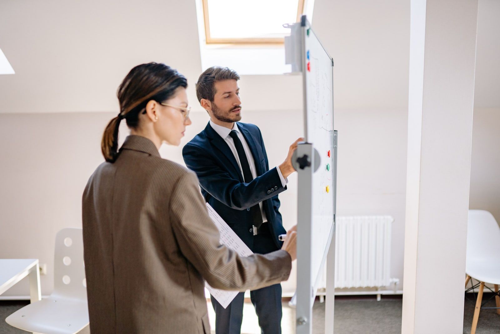 Two colleagues working at a whiteboard in an office