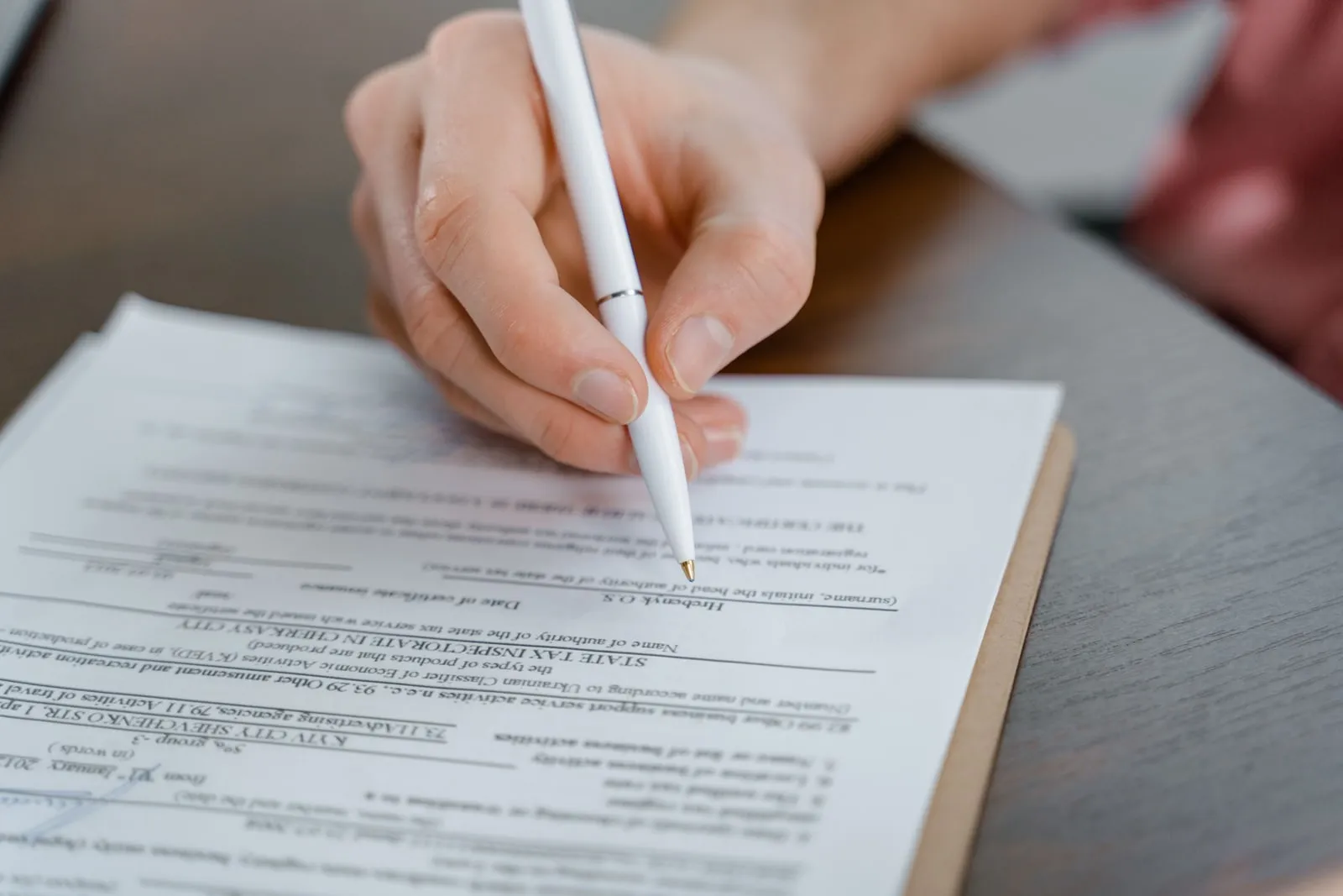 An open legal document and a pen on a wooden desk