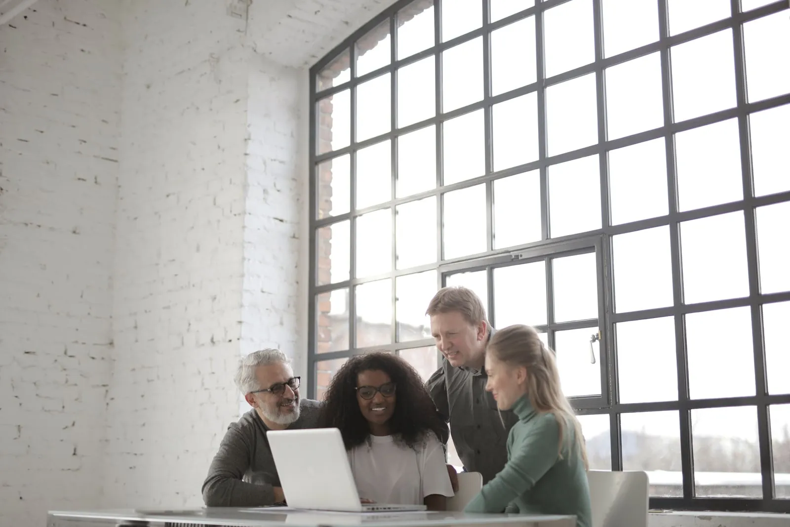 Colleagues meeting around a laptop in an office