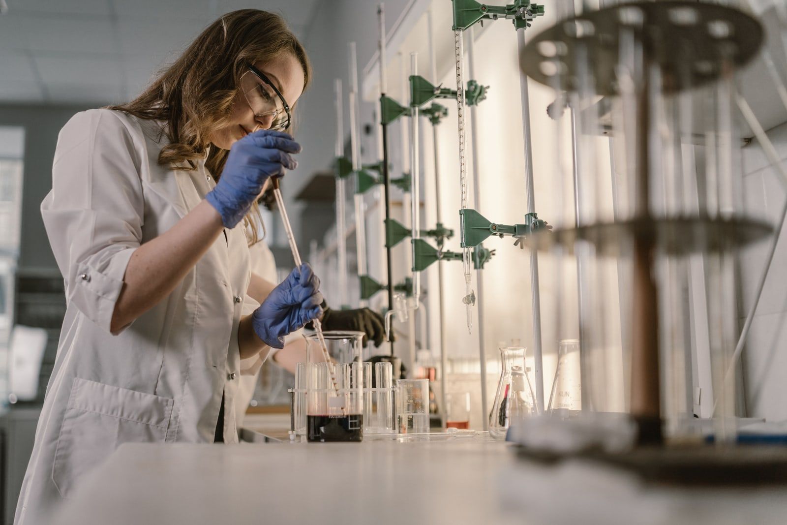 A scientist in a white coat using a pipette at a laboratory bench