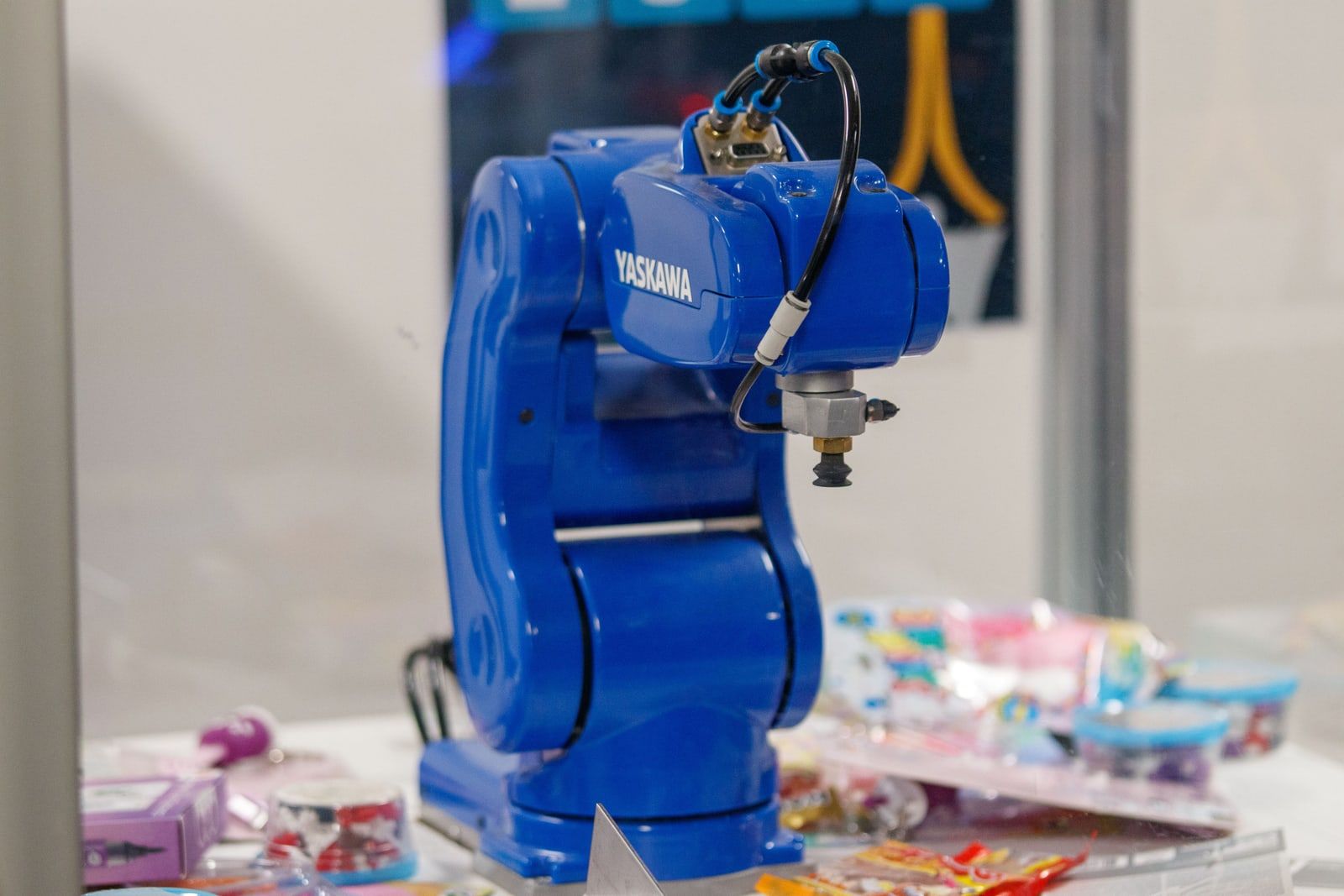 An industrial robotic arm with a suction gripper above a table of small items