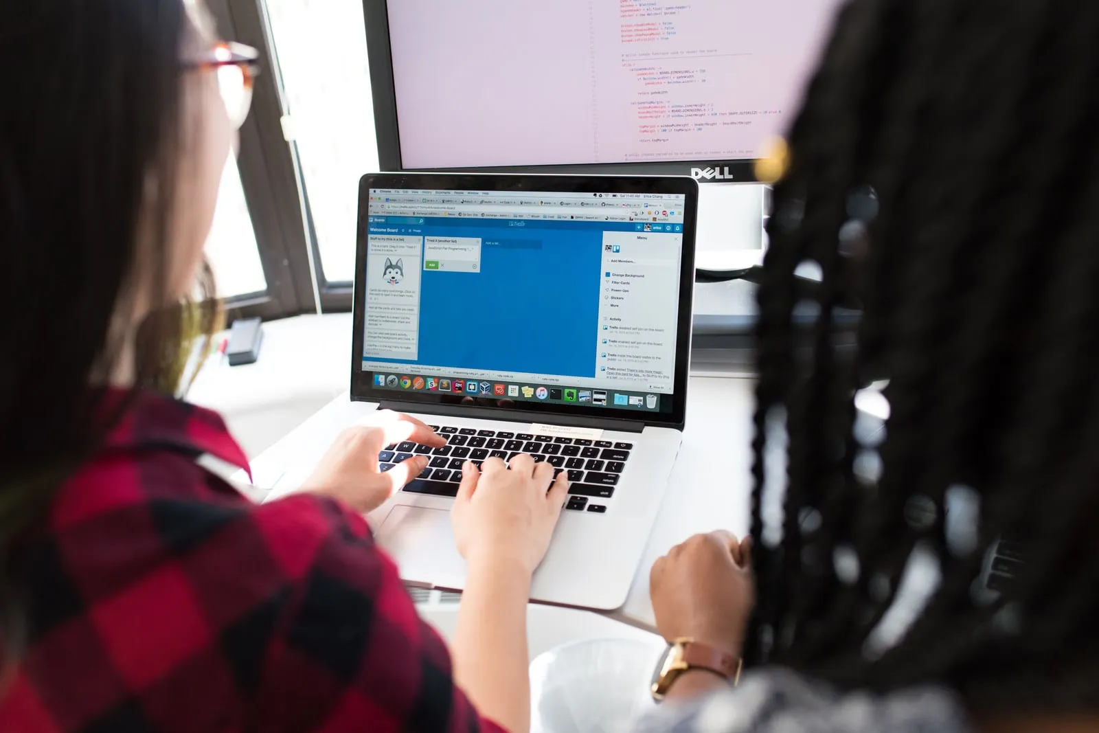Two people working at computers in a bright office