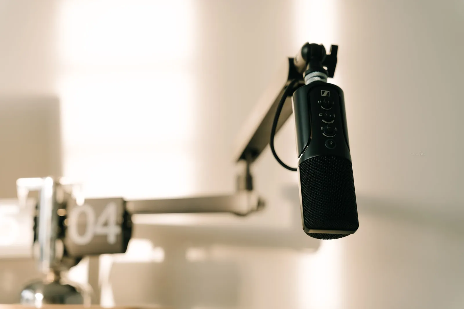 A studio microphone on a boom arm in a small recording room