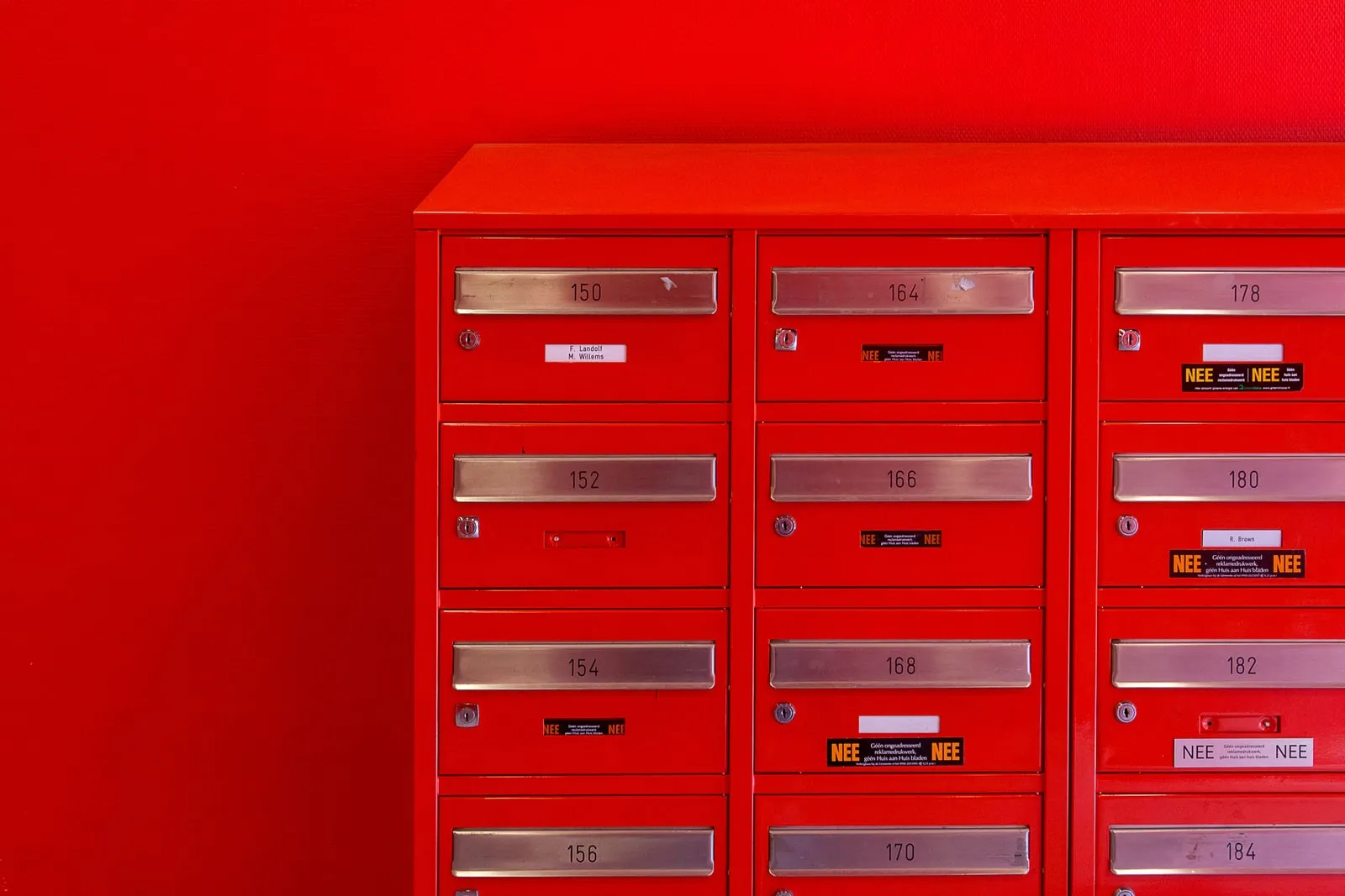 A row of numbered red metal mailboxes on a wall