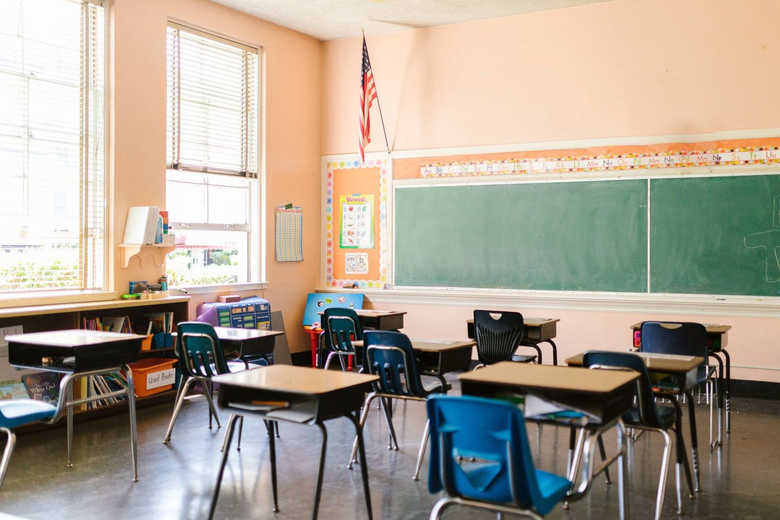 An empty elementary school classroom with rows of small wooden desks and chairs