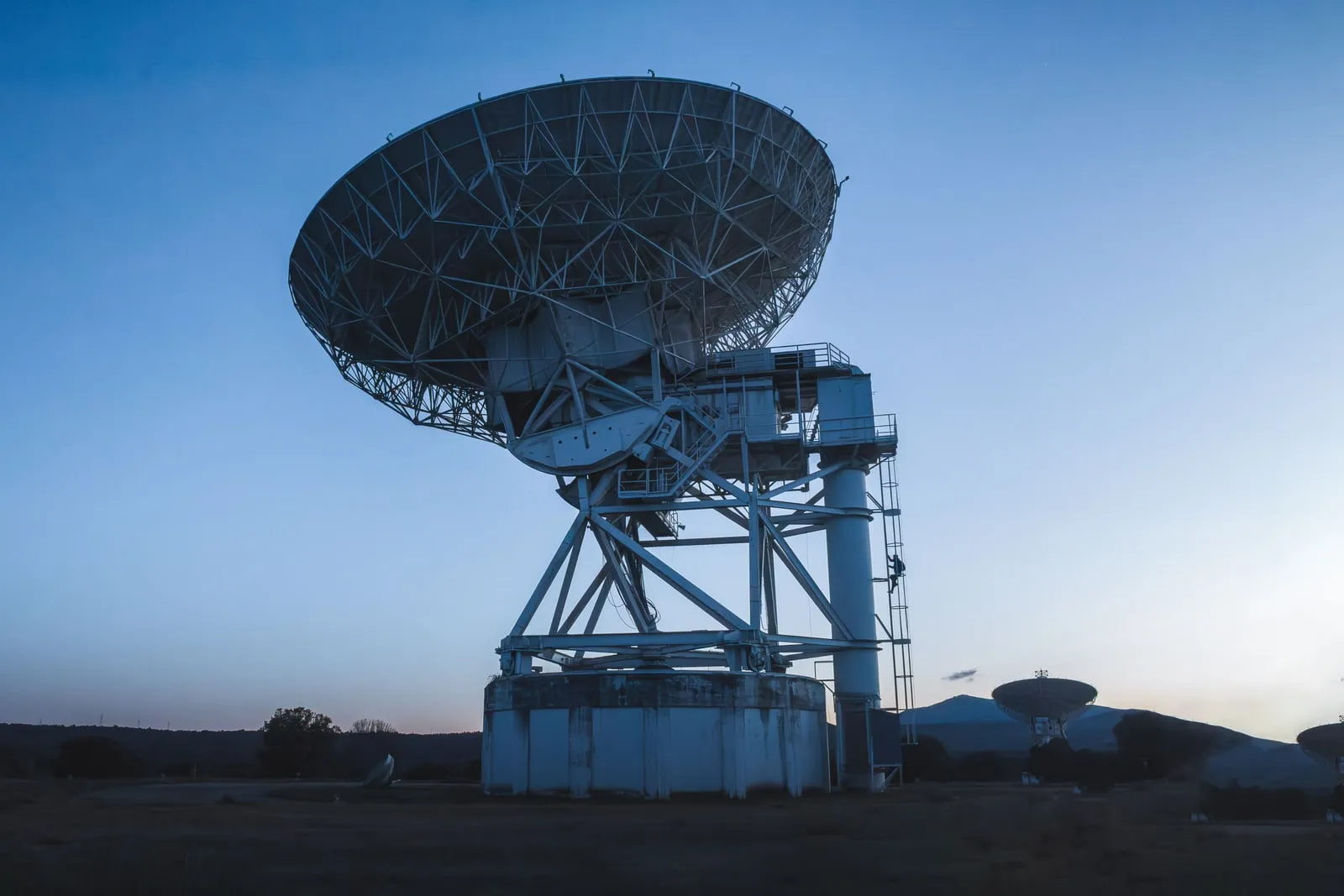 A radio telescope dish against a twilight sky