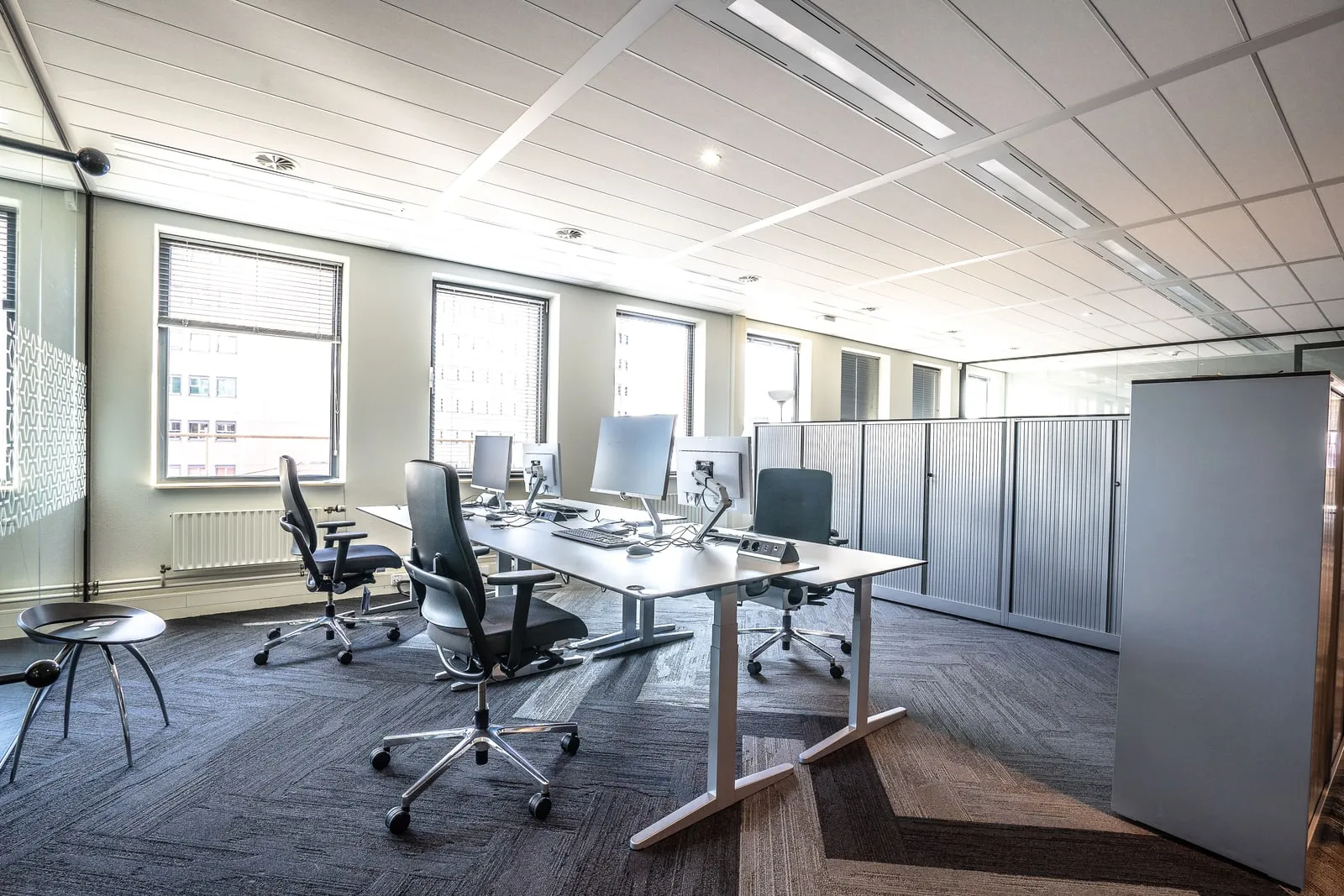 A bright open-plan technology office with rows of empty workstations