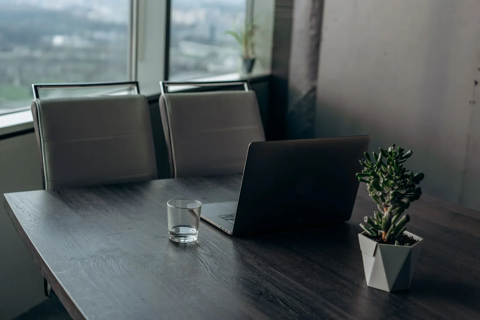 An open laptop on a meeting-room table beside a window
