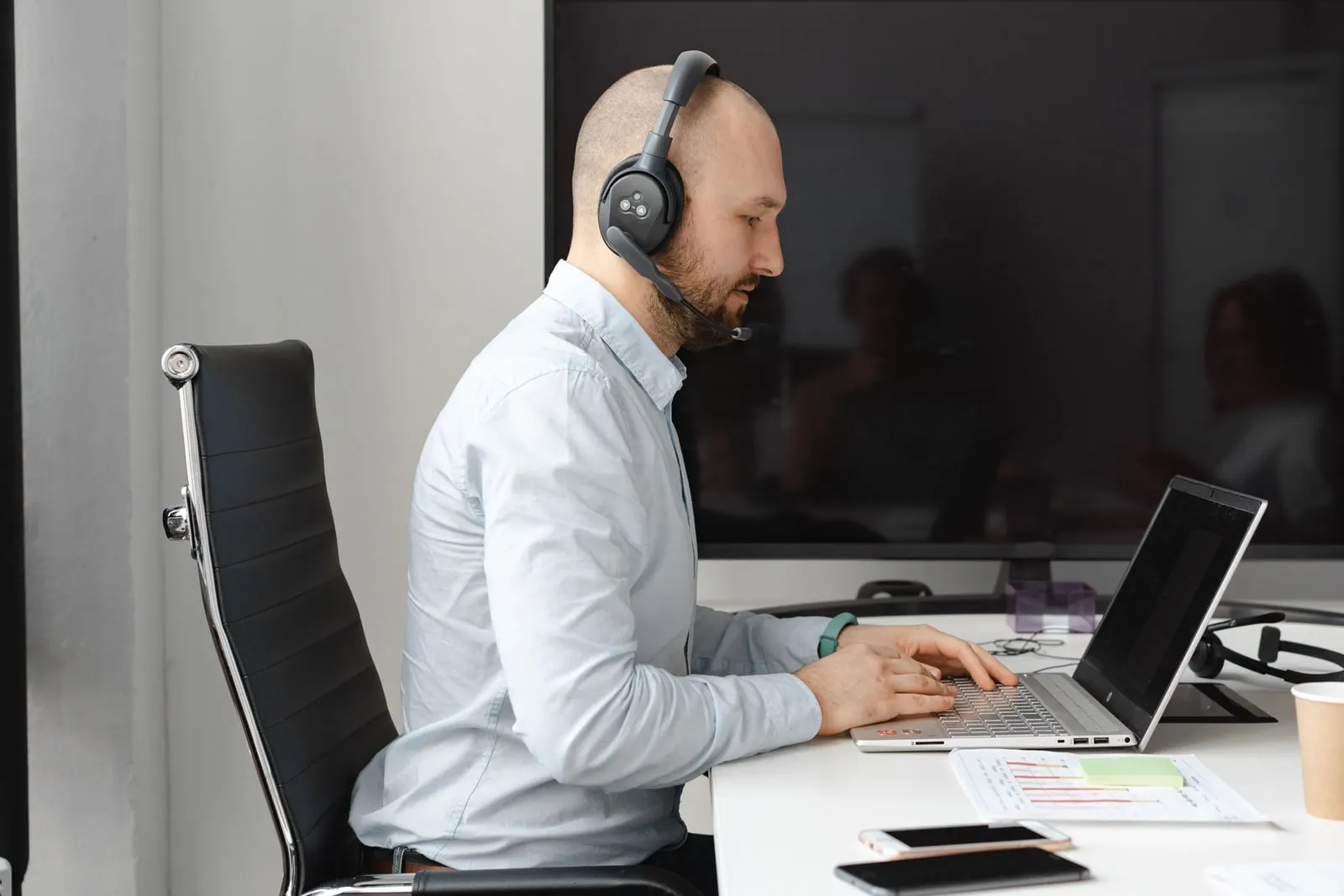A person wearing headphones working on a laptop at a desk
