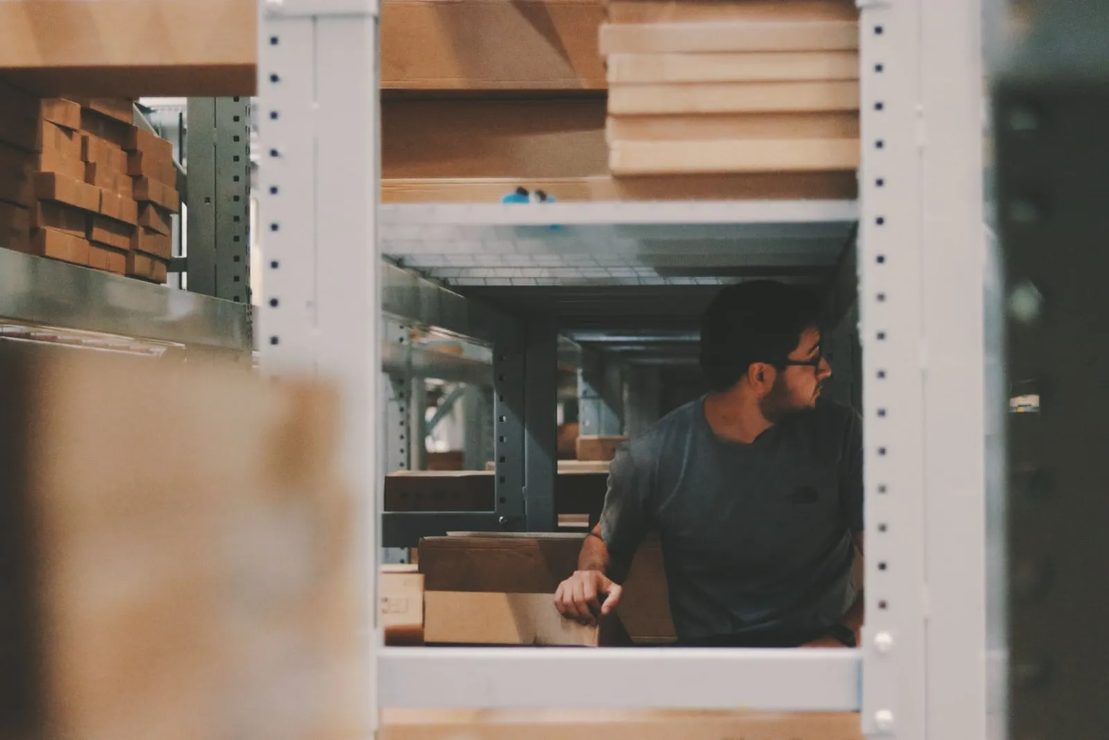 A worker moving boxes on a warehouse shelf