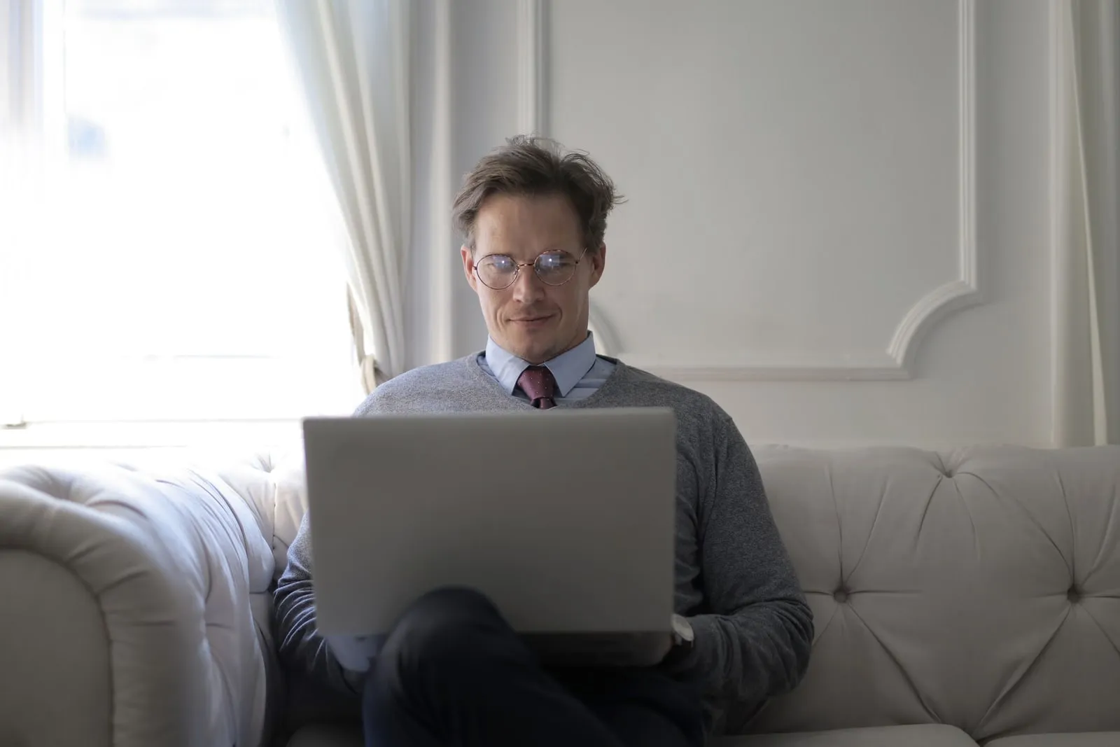 A man in a shirt and tie reading something on a laptop