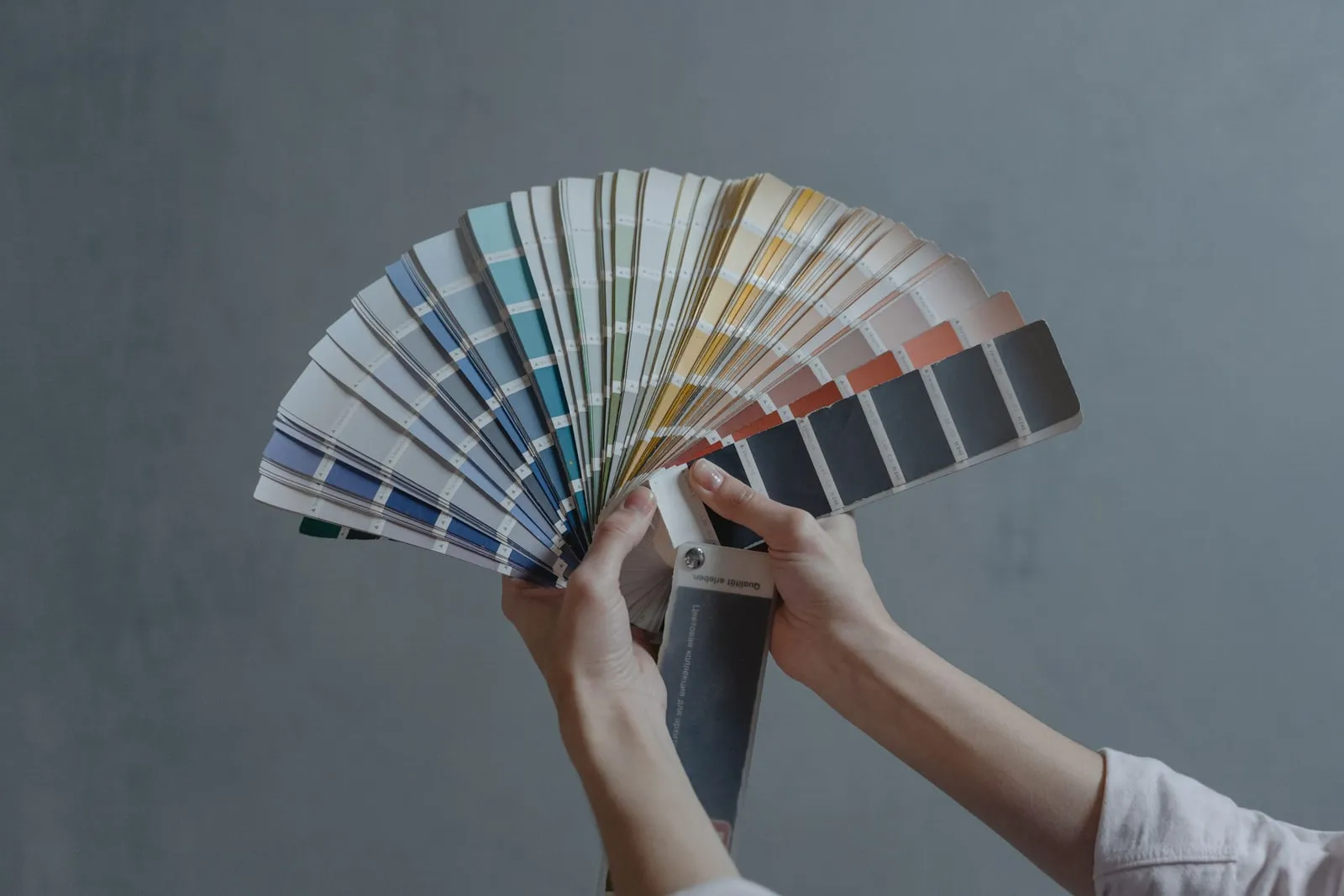 Hands holding an opened fan of paint colour swatches