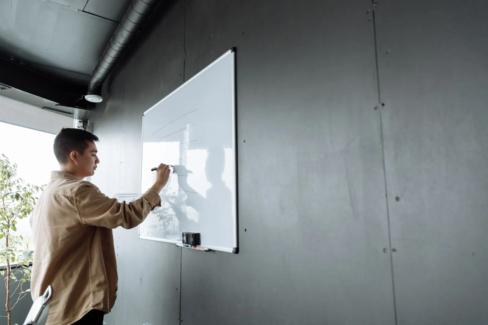 A person writing on a whiteboard in an office