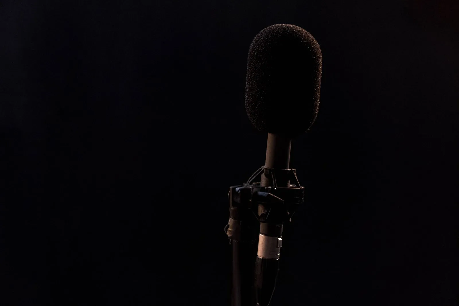 Un seul microphone sur pied devant un fond sombre uni