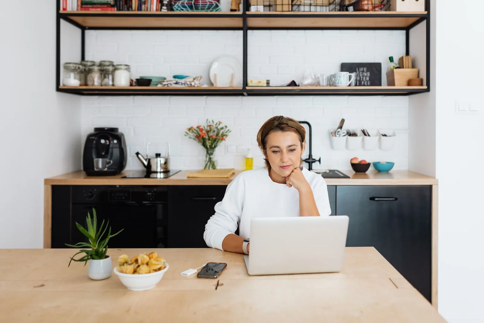A person working on a laptop at a kitchen table