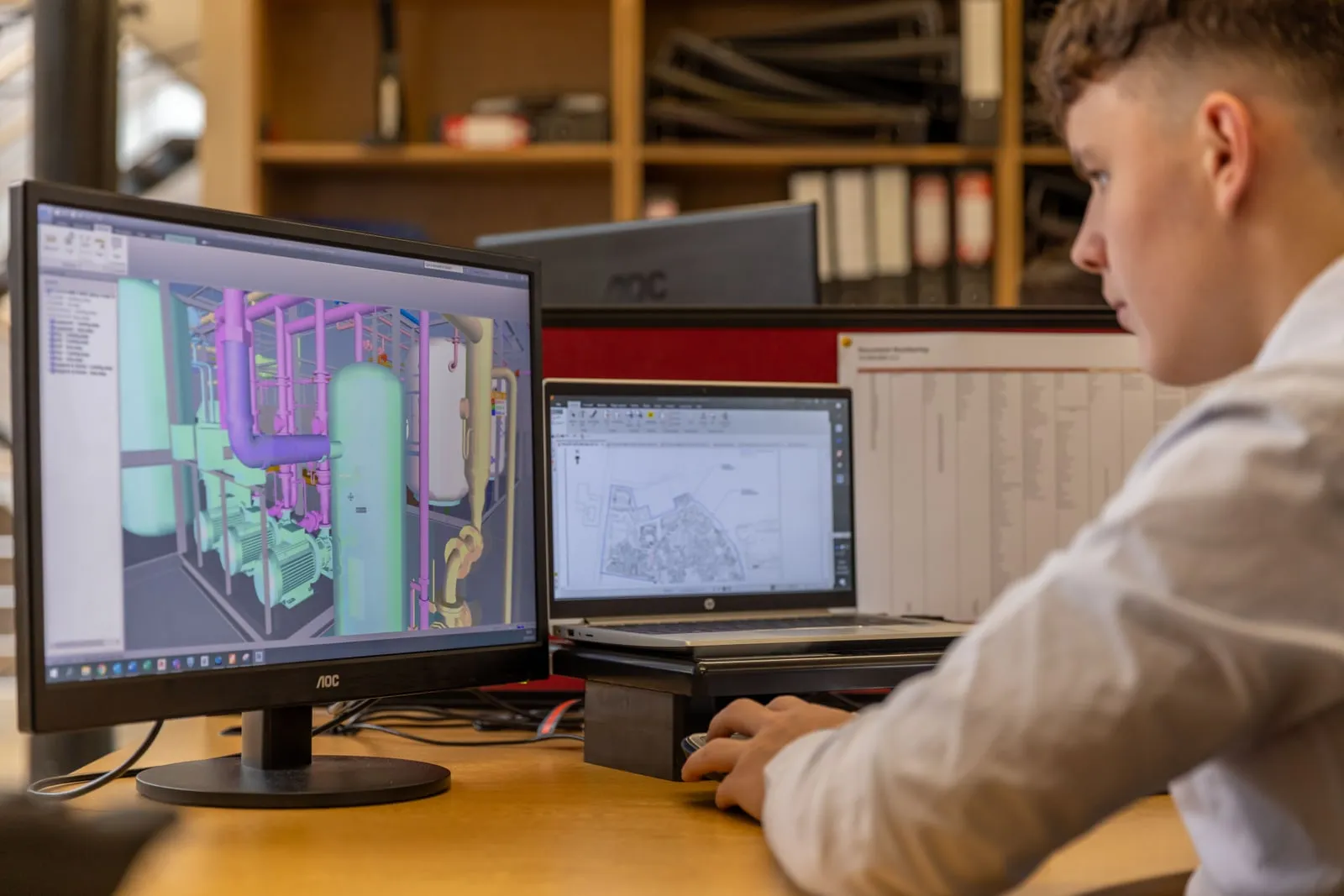 An engineer working at a desk in front of several computer monitors