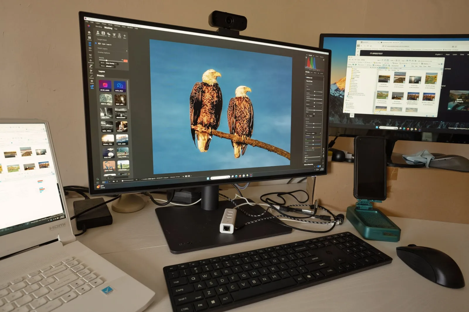A wide desktop monitor displaying a colourful image being edited.