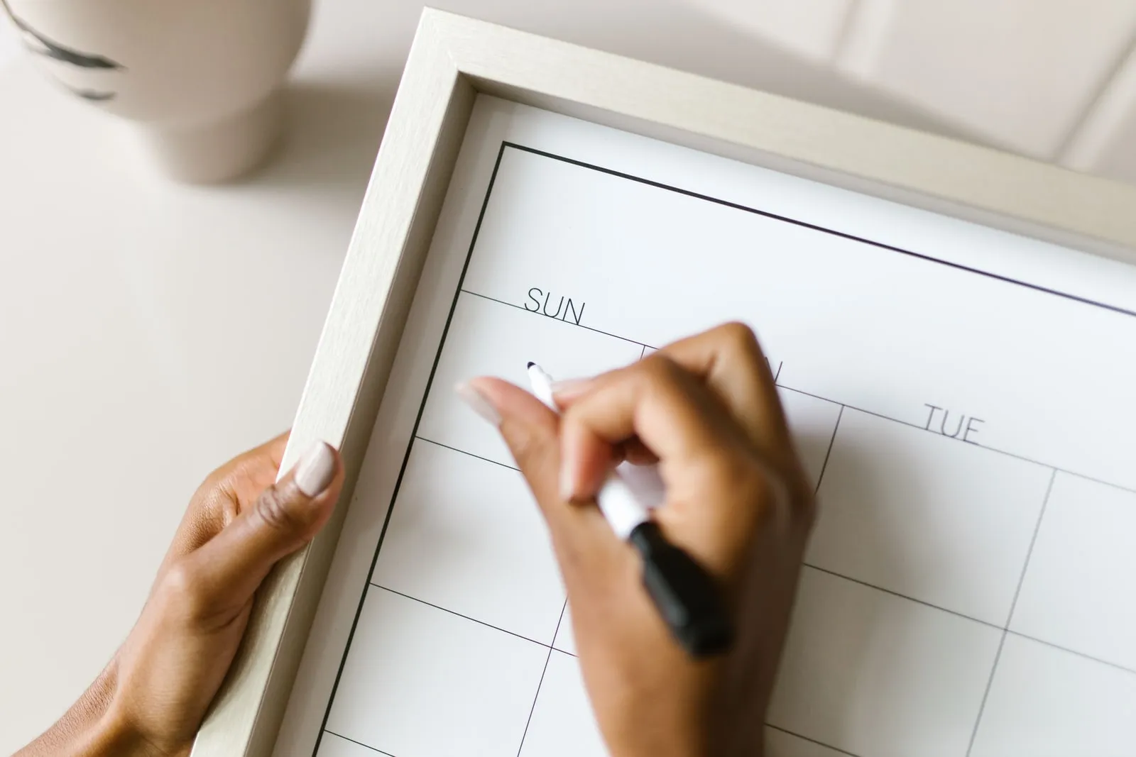 Hands marking a date on a blank wall calendar